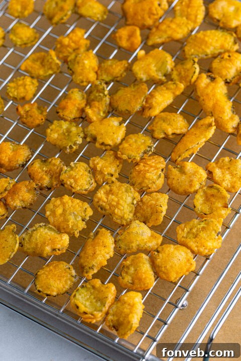 Fried pickles being removed from hot oil with a slotted spoon.