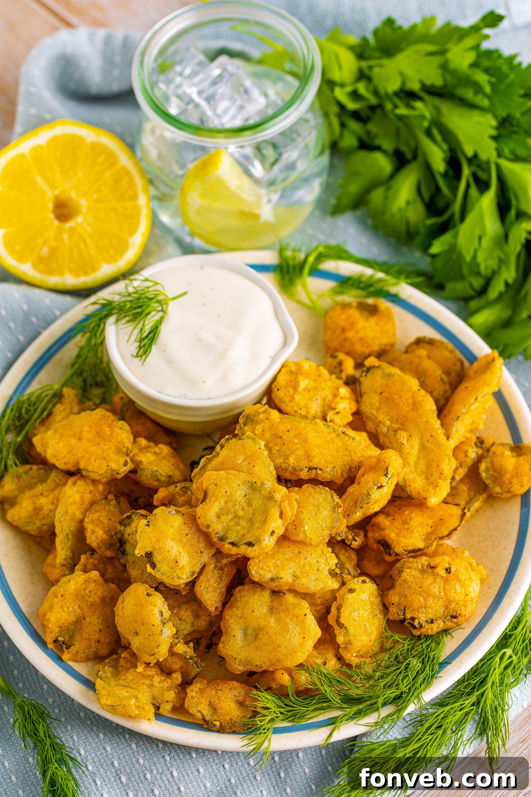 Overhead view of Fried Pickles on a white plate with ranch and fresh dill in the background. 