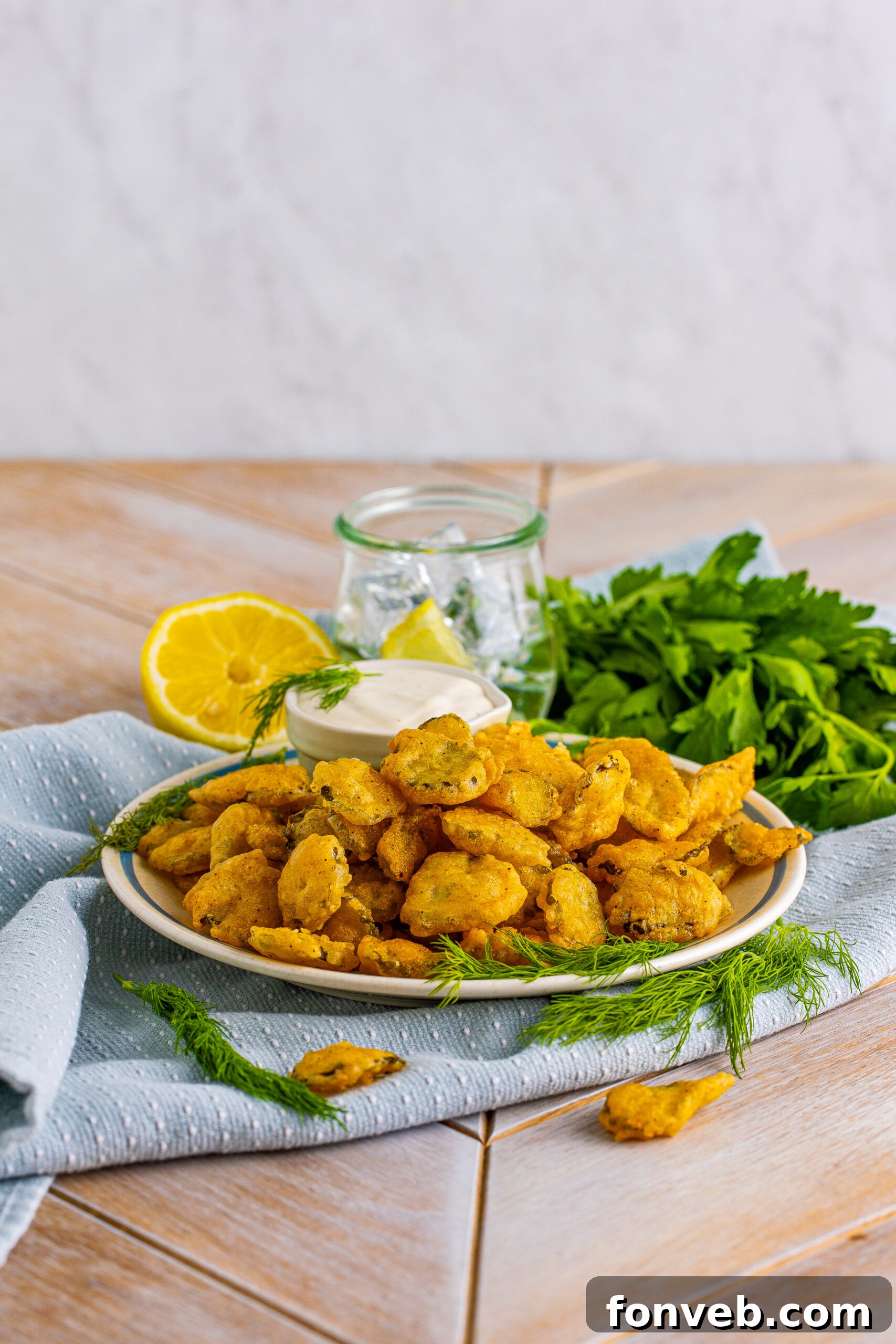 Fried Pickles on a white plate with ranch and fresh dill in the background. 