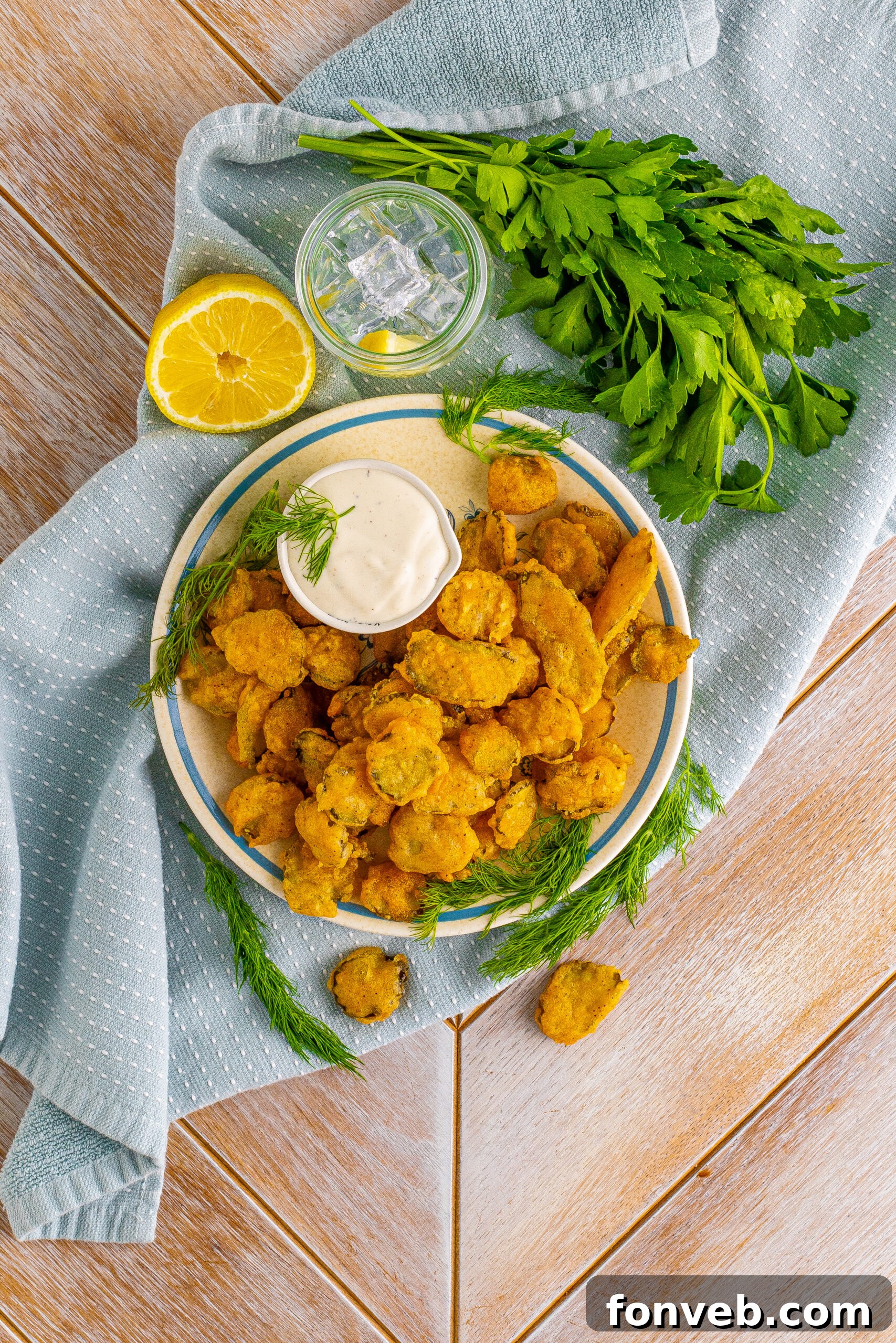 Overhead view of Fried Pickles on a white plate with ranch and fresh dill in the background. 