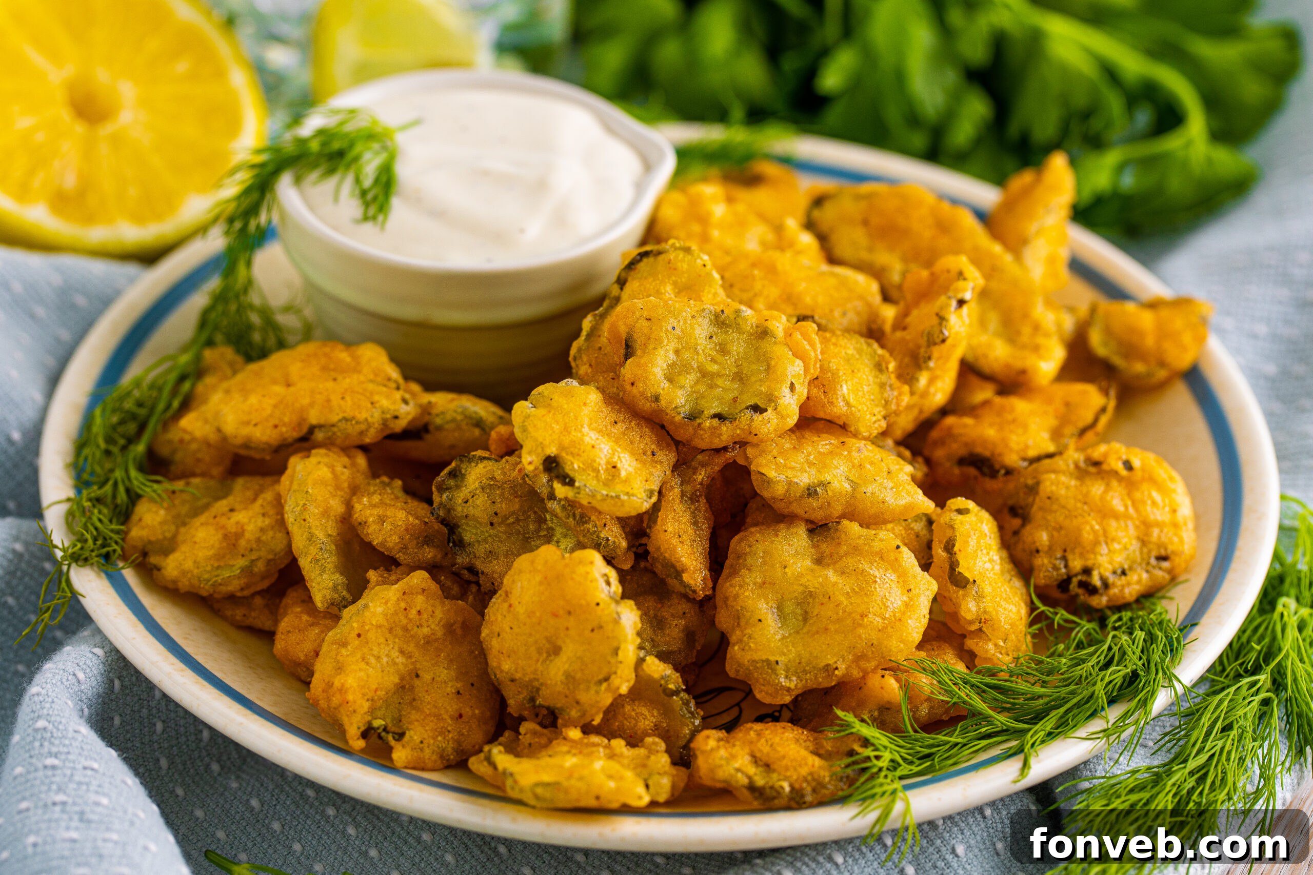 Close up shot of Fried Pickles on a white plate with ranch and fresh dill in the background. 
