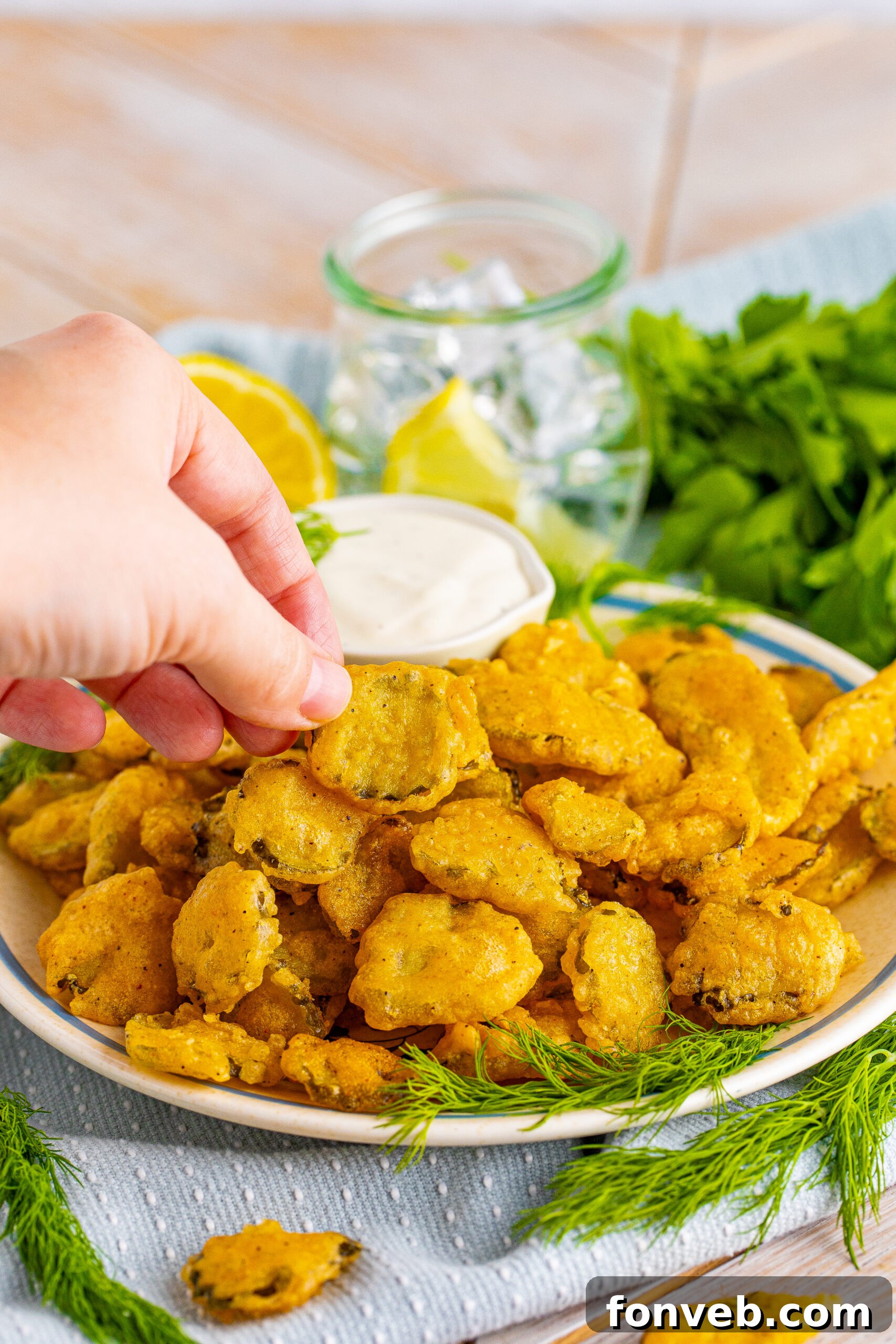 A hand removing a Fried pickle from the plate. 