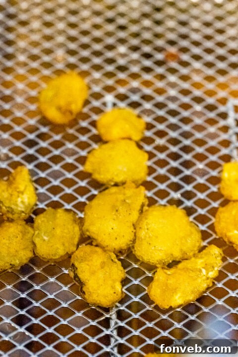 Pickle slices being tossed in the prepared batter.