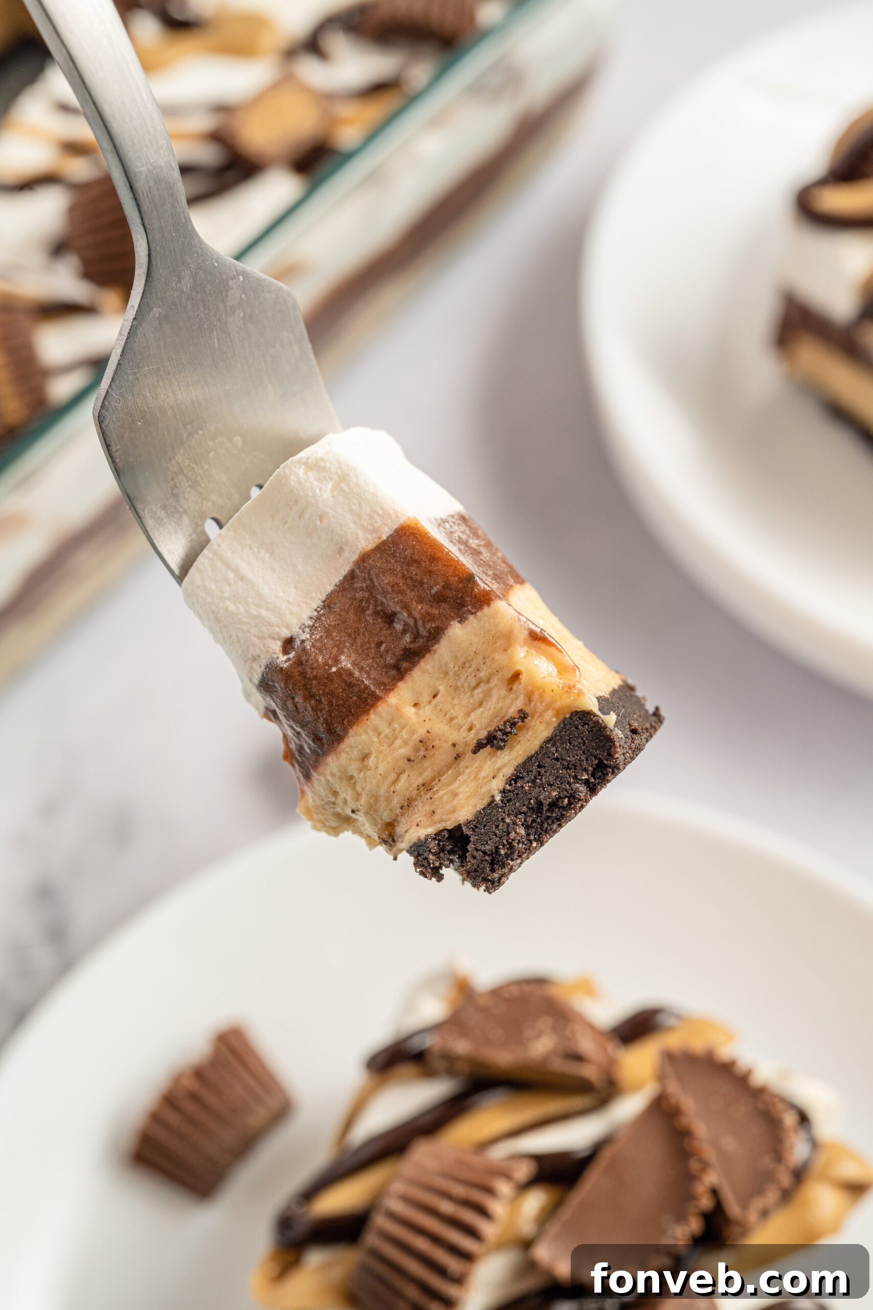 Reese's Peanut Butter Cup Lasagna 15 A fork piercing into a delectable bite of chocolate lasagna, highlighting its soft and creamy layers.