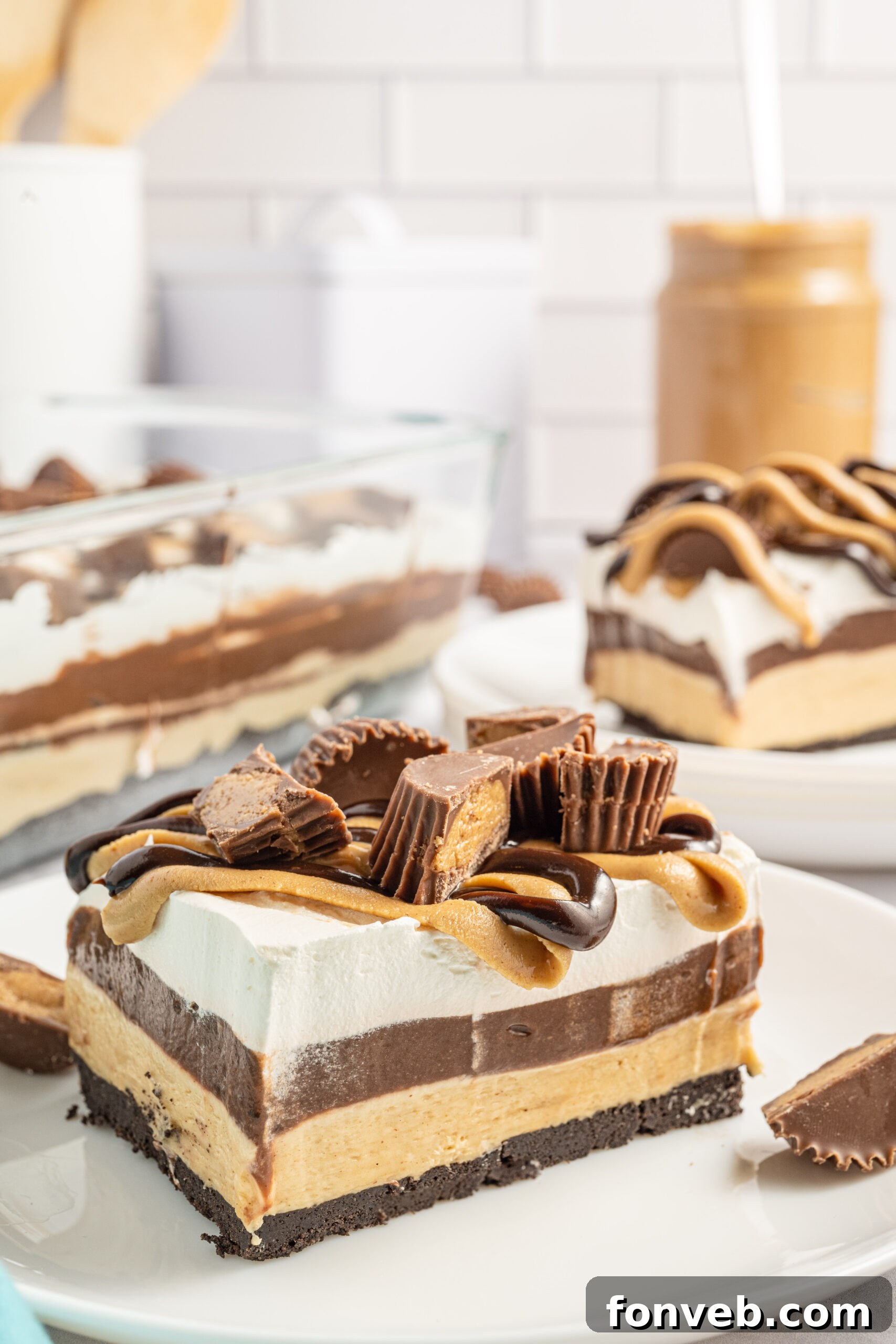 Reese's Peanut Butter Cup Lasagna 6 Two generous pieces of chocolate peanut butter lasagna served on elegant white plates, with a jar of creamy peanut butter strategically placed in the background.