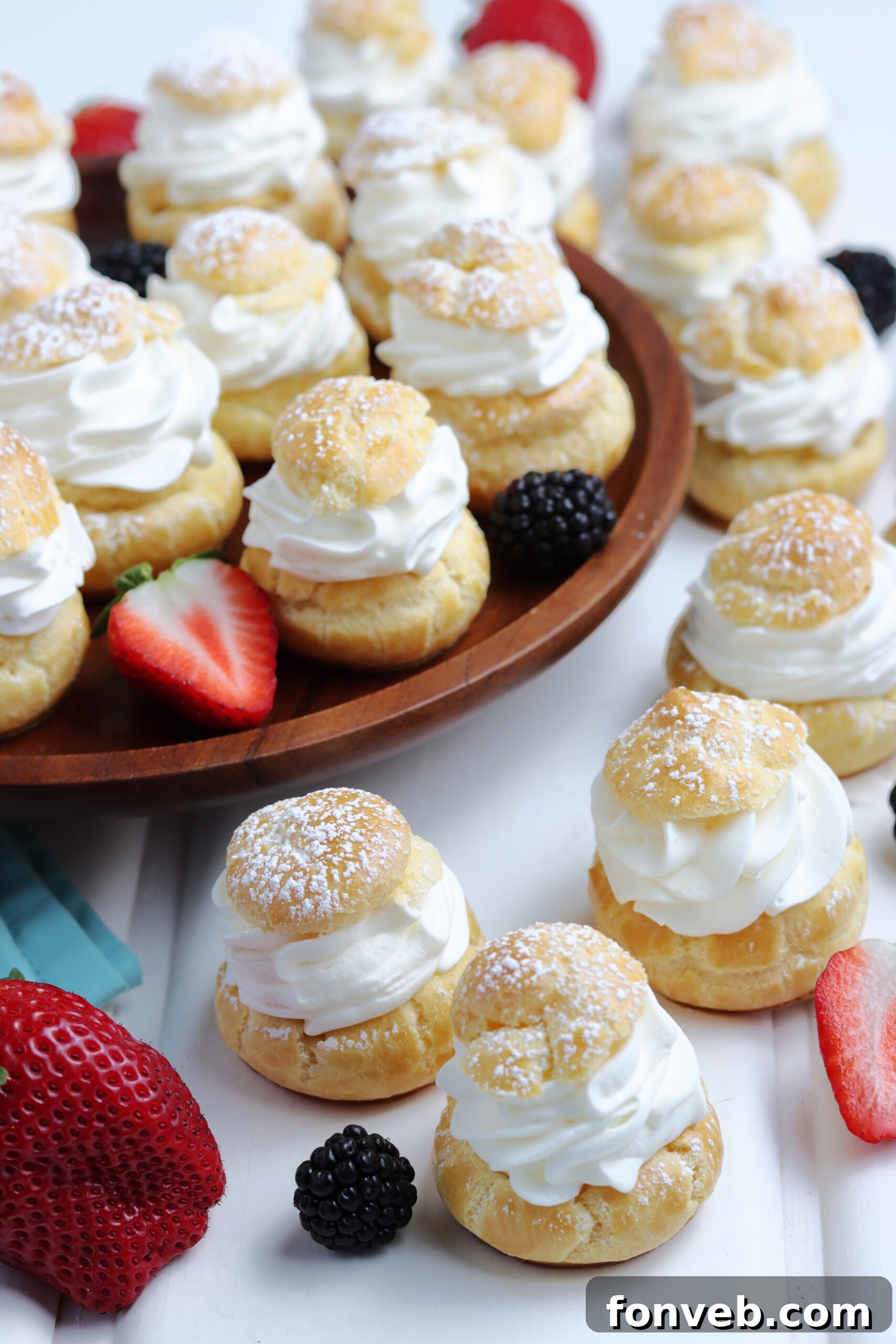 Overhead shot of cream puffs elegantly arranged with fresh berries and a dusting of powdered sugar, emphasizing their beauty.