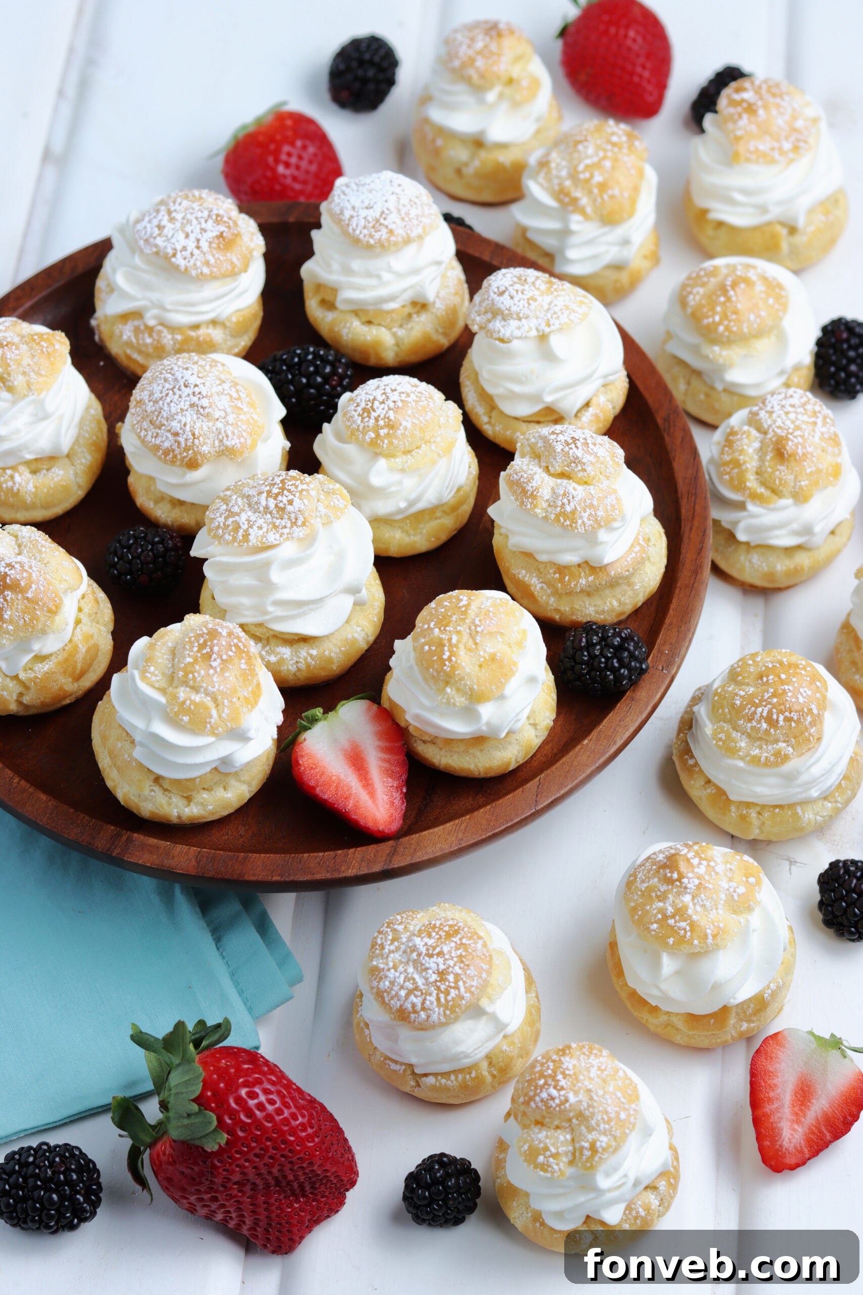 Overhead shot of an arrangement of cream puffs dusted with powdered sugar and garnished with fresh berries.