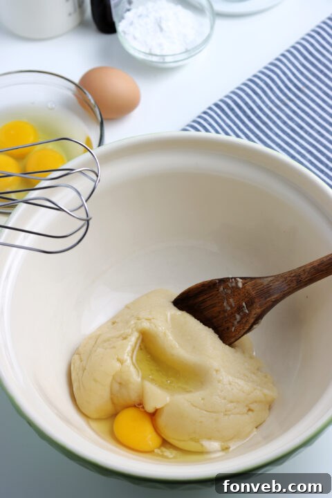Close-up of freshly piped choux pastry shells on parchment paper, ready for baking.
