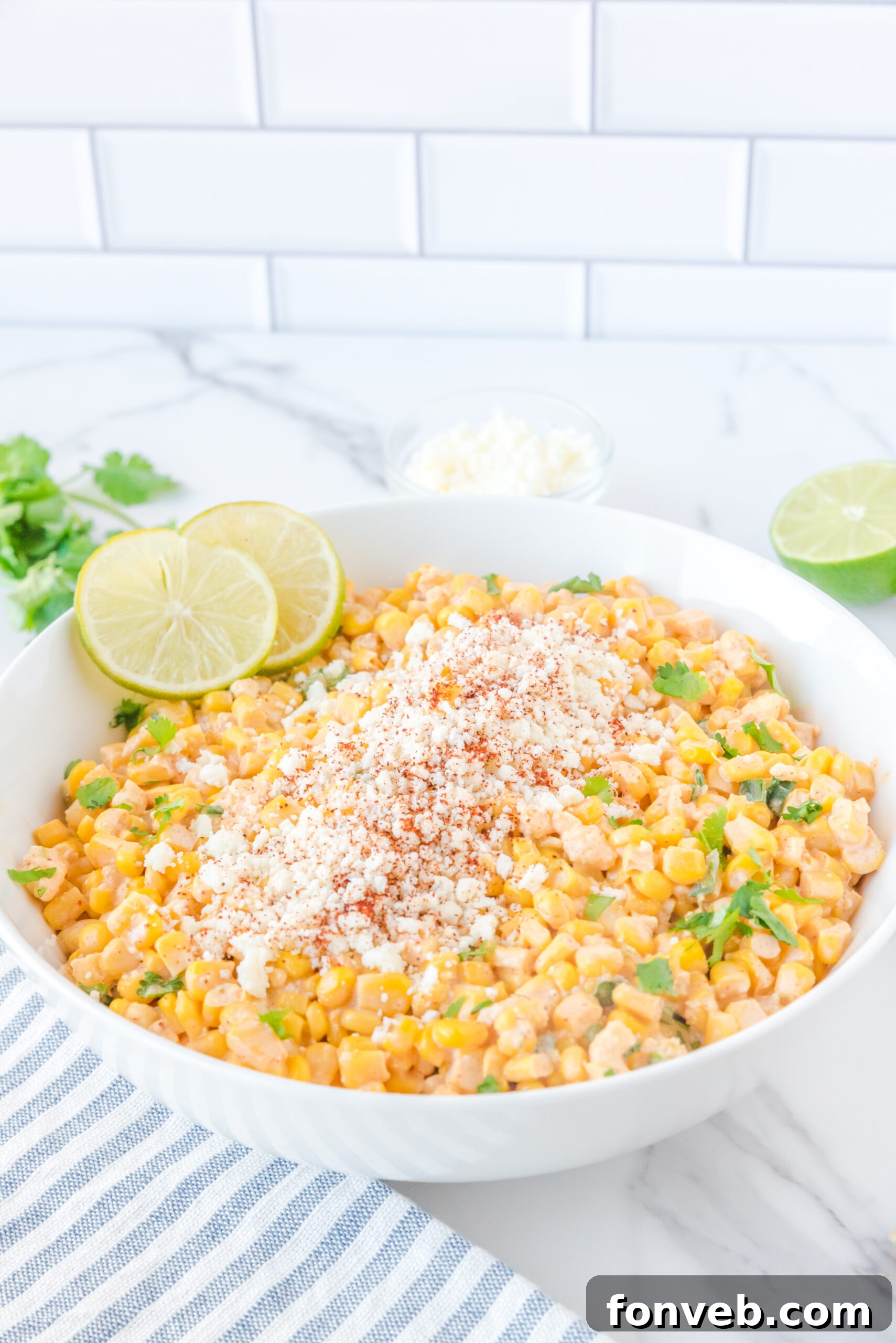 A large white serving bowl filled with the inviting Mexican Street Corn Salad, showcasing its vibrant colors and creamy texture.
