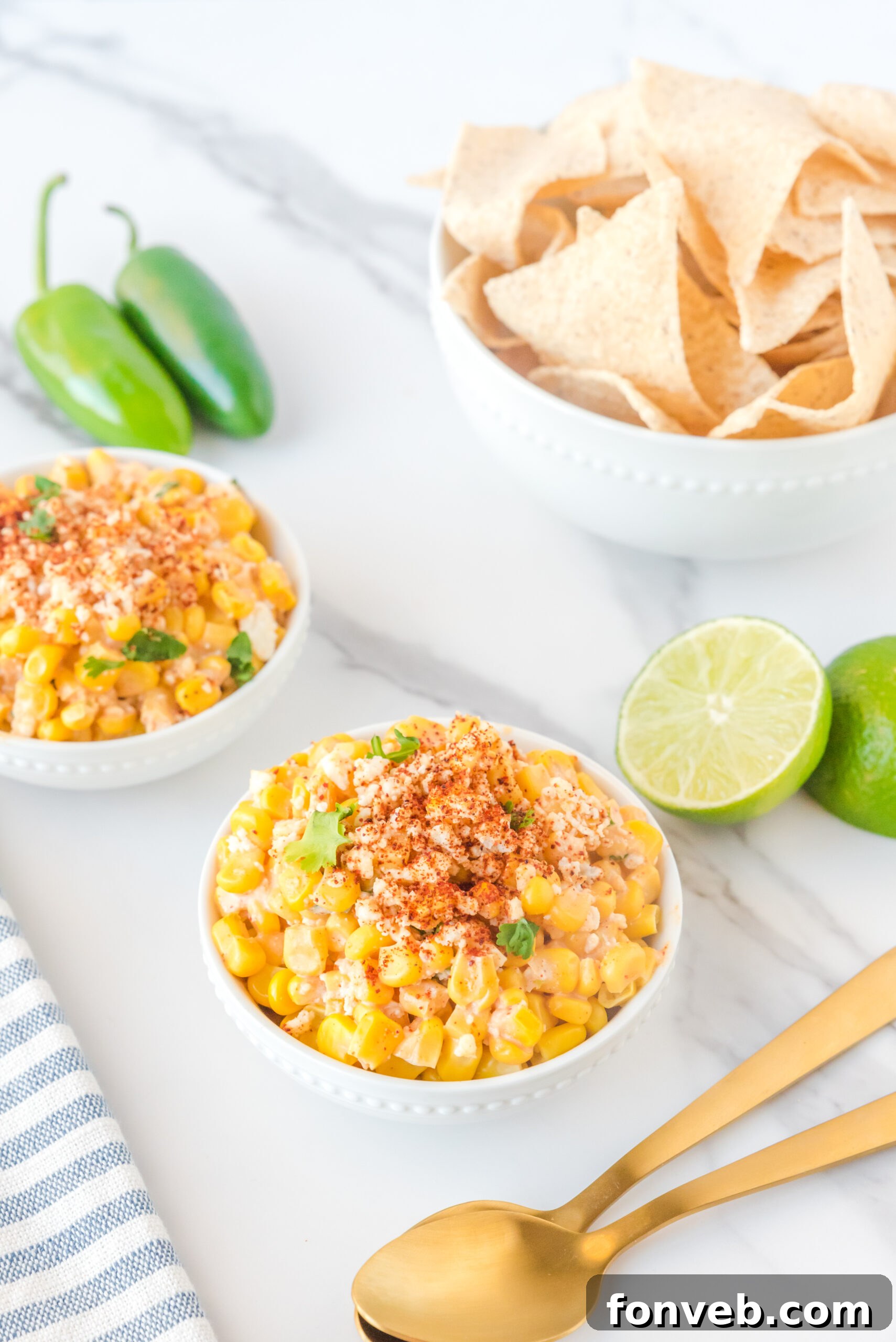 Two individual white bowls showcasing Mexican Street Corn Salad, beautifully adorned with a dusting of paprika and generous crumbles of fresh queso fresco.