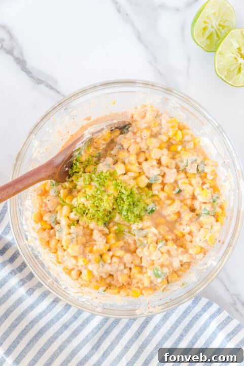 The creamy mayonnaise and heavy whipping cream being stirred into the corn mixture, forming the rich dressing base.