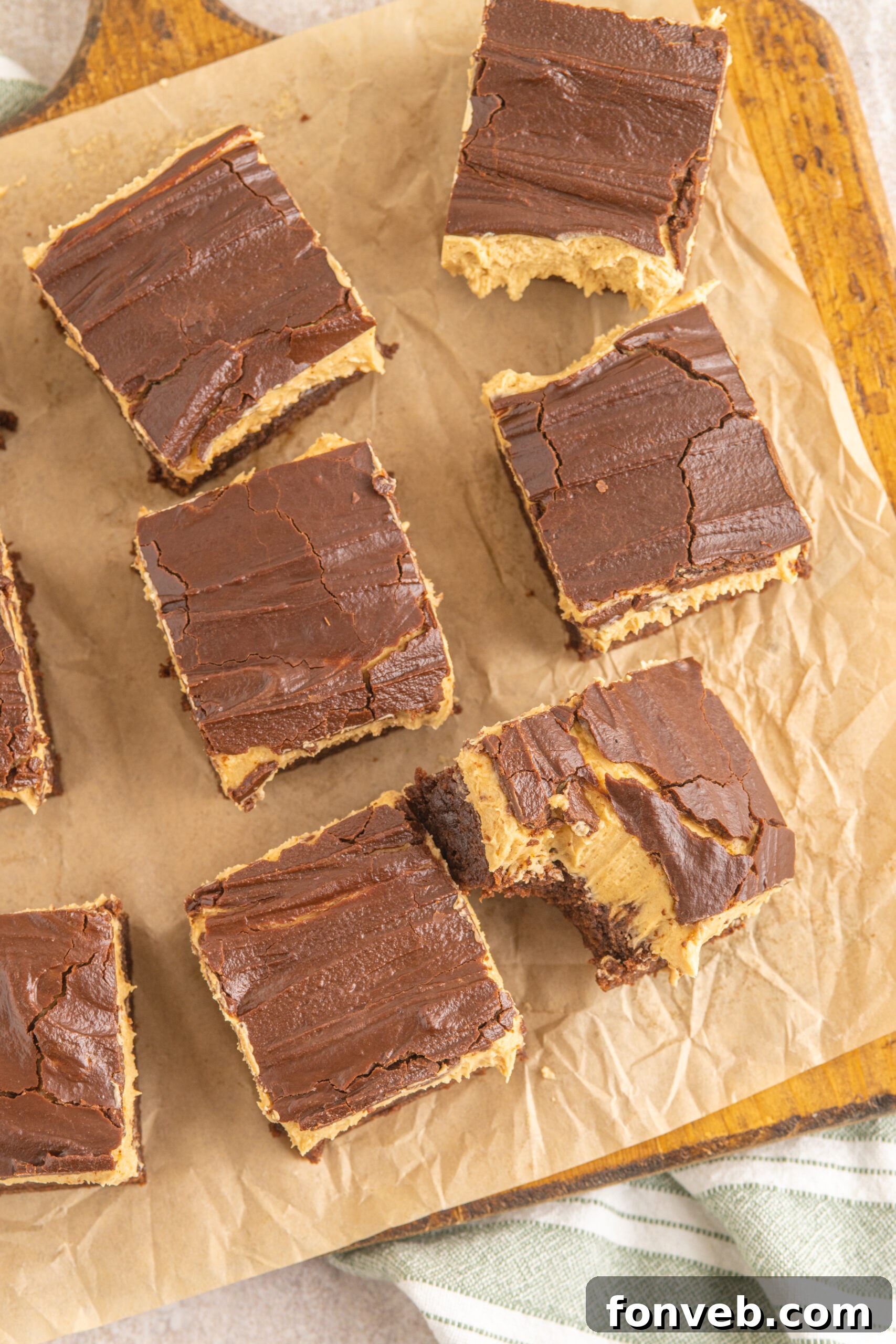 A beautiful overhead shot of a batch of Buckeye Brownies arranged on a wooden board with baking parchment, highlighting their uniform layers.