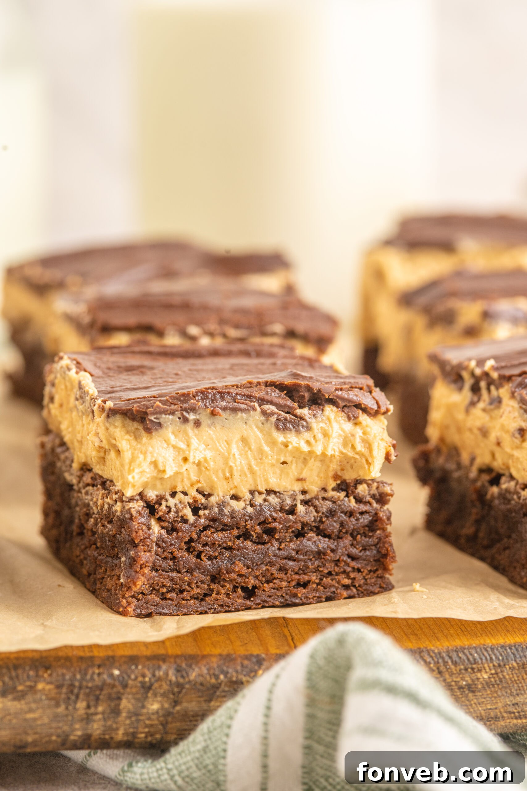A clear side view of a Buckeye Brownie, highlighting the three distinct and delicious layers: fudgy chocolate brownie, creamy peanut butter frosting, and shiny chocolate ganache.