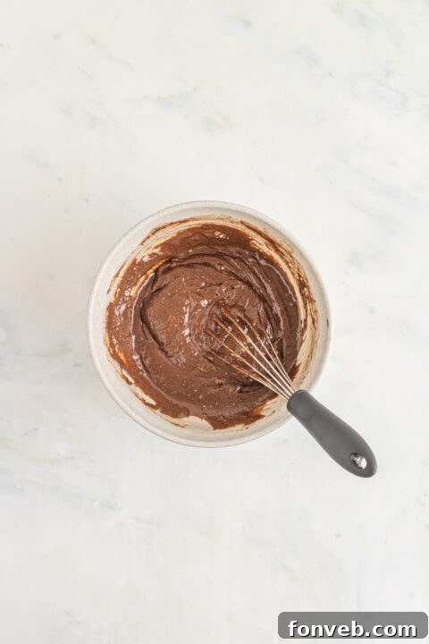 Close up of a bowl with brownie mix and other ingredients, ready for mixing.