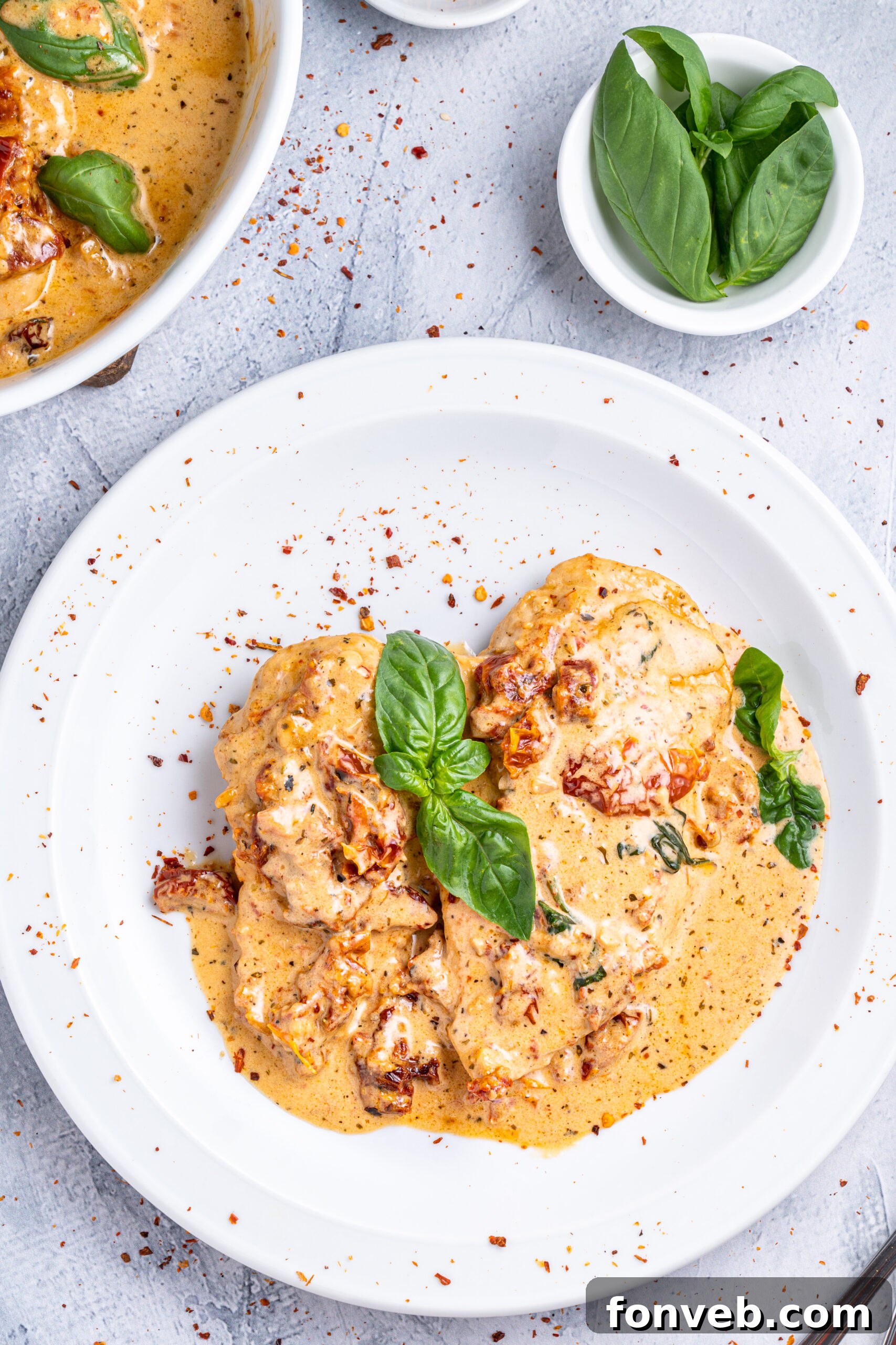 Dreamy Date Night Chicken 14 Marry Me chicken on a white plate topped with fresh basil and pepper flakes.