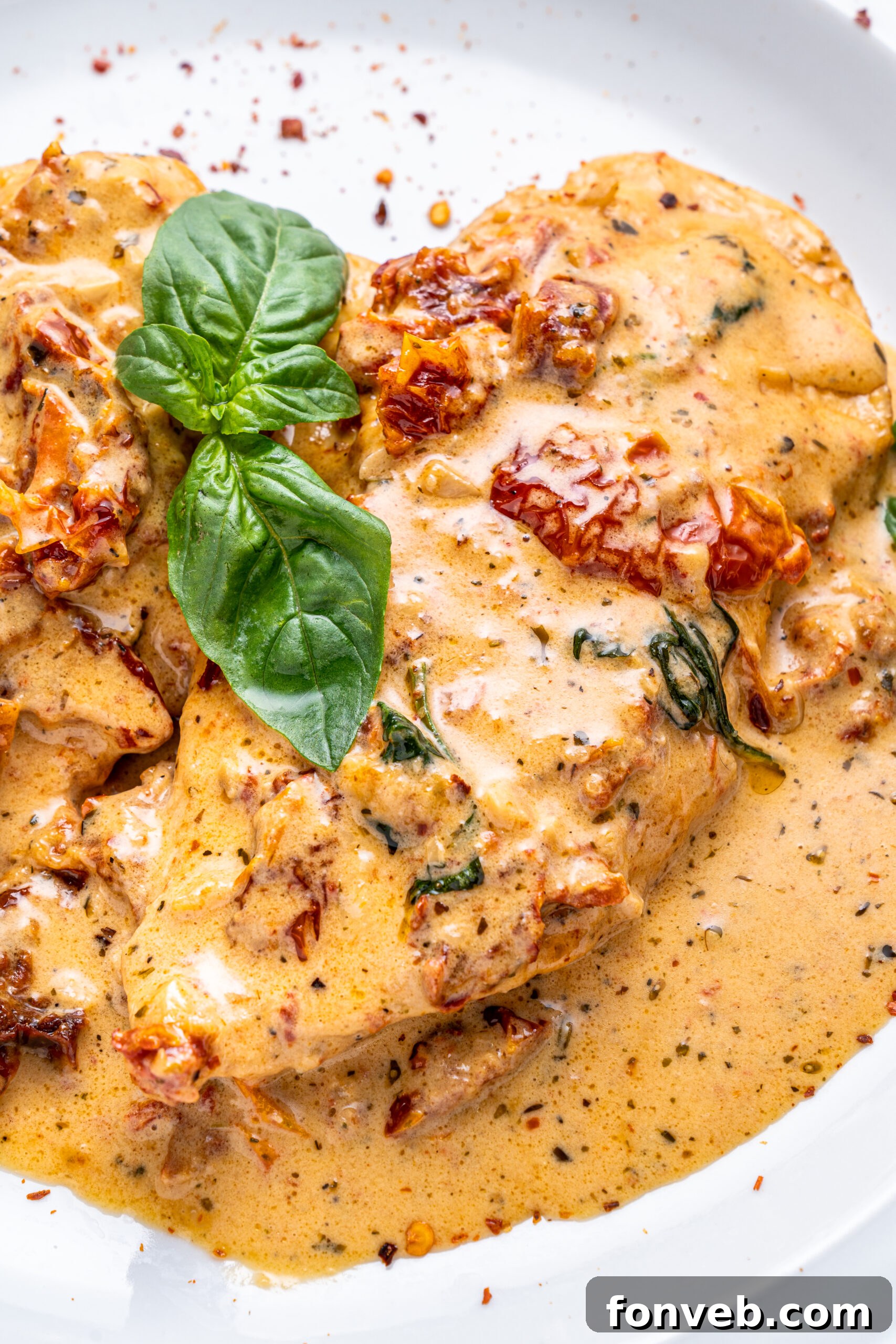 Dreamy Date Night Chicken 15 Close up shot of Marry Me chicken on a white plate topped with fresh basil and pepper flakes.