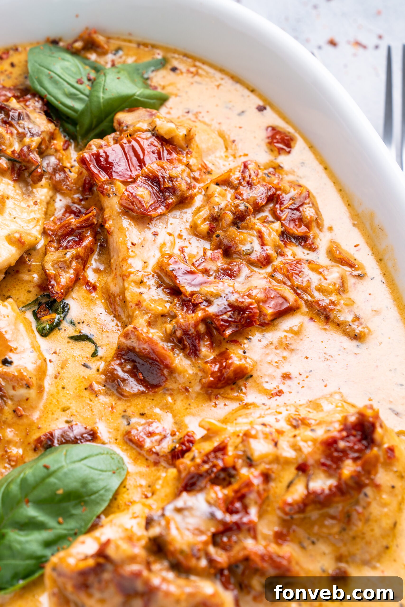 Dreamy Date Night Chicken 17 Close up shot of Marry Me Chicken in a white baking dish topped with fresh basil.