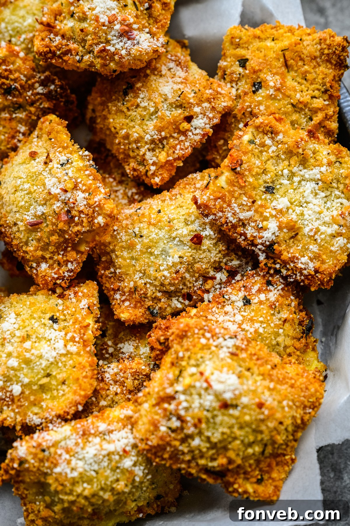 Close up overhead view of Air Fryer Ravioli in a black serving tray with parchment paper and marinara sauce. 
