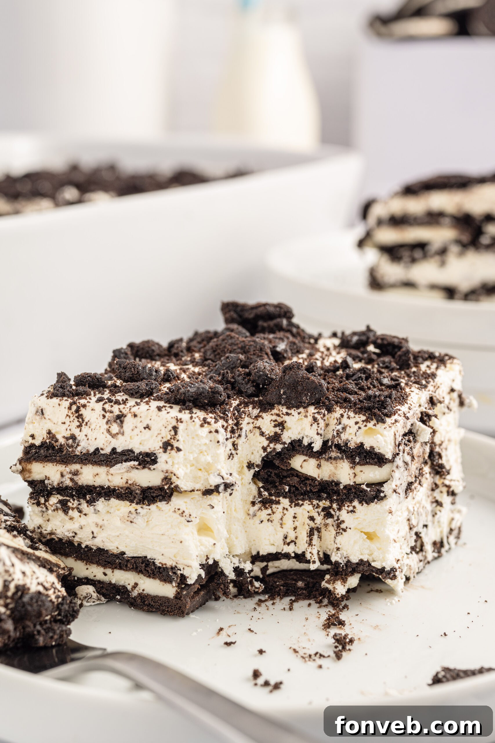 Slice of the Oreo Icebox Cake on a white plate with a bite missing