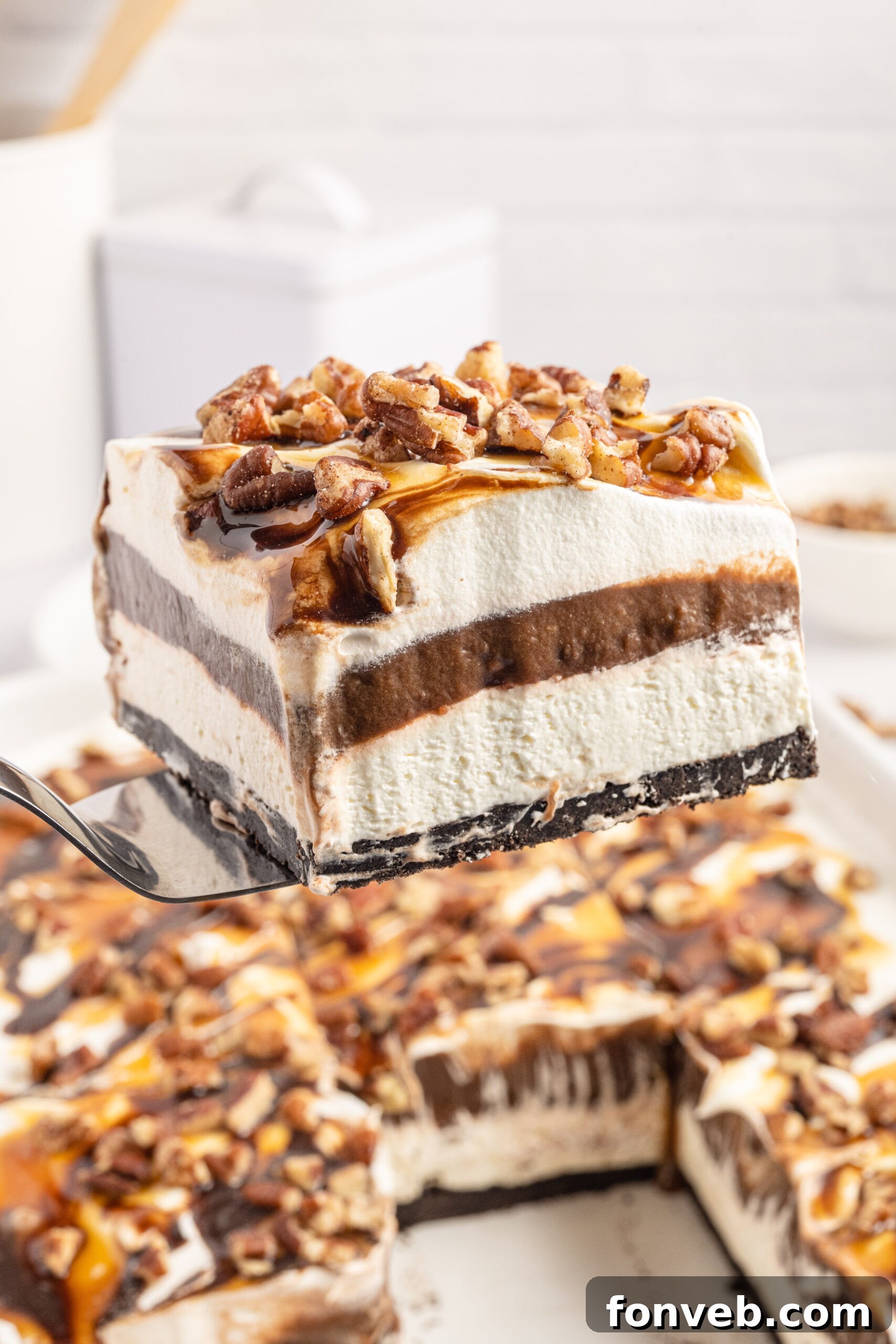 Front view of a slice of Turtle Lush on a silver cake server, showcasing its delicious layers.