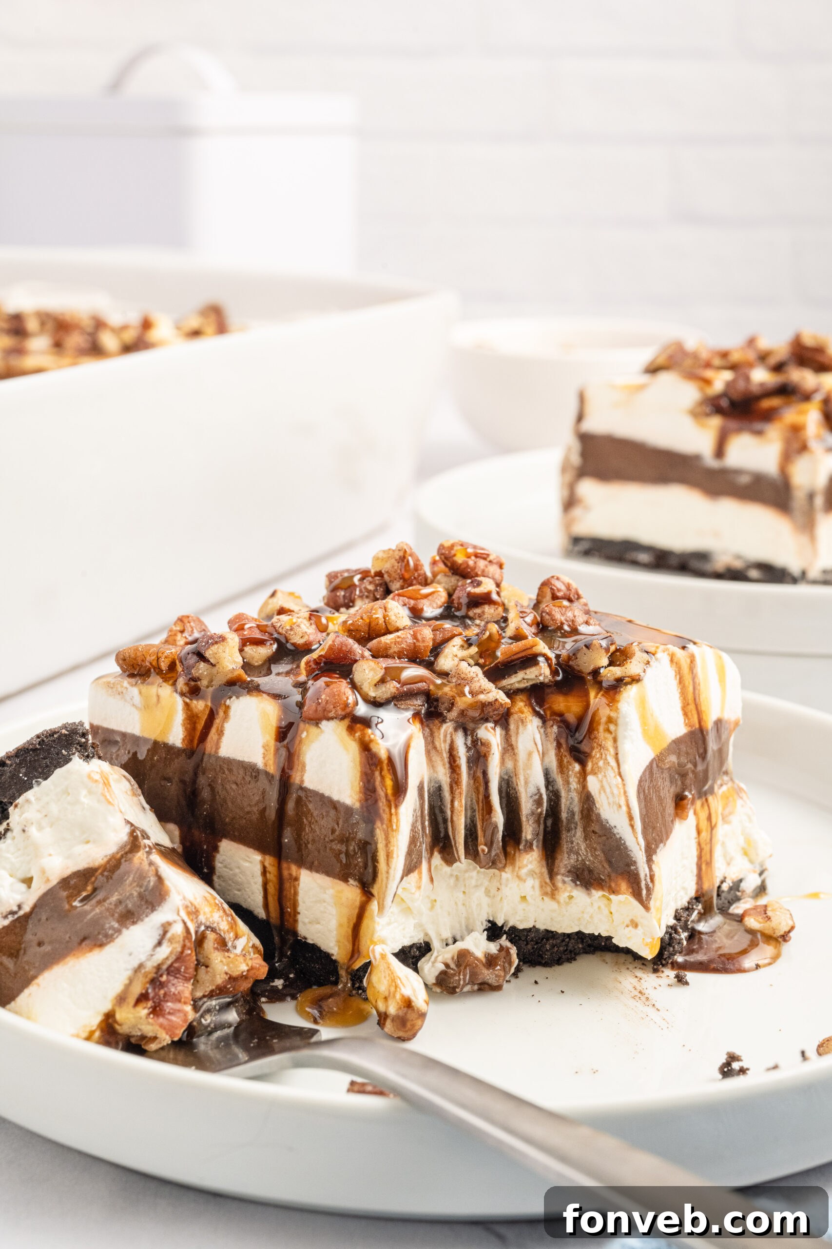 Front view of a slice of Turtle Lush on a white plate with a bite removed by a silver fork, showing the creamy interior.