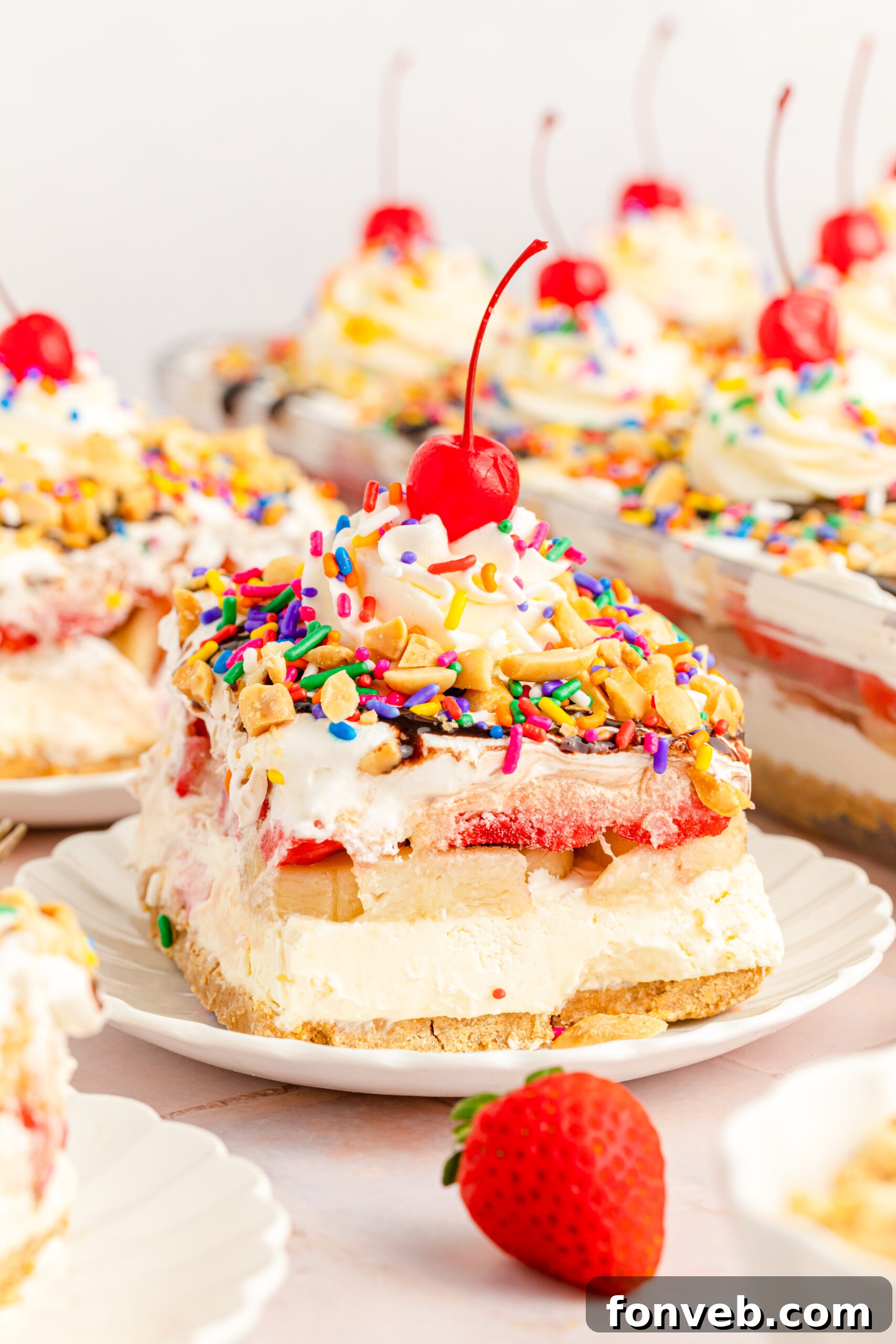A tempting front view of a thick slice of No-Bake Banana Split Cake, highlighting the distinct layers of crust, rich cream cheese, fruit, and fluffy whipped topping.