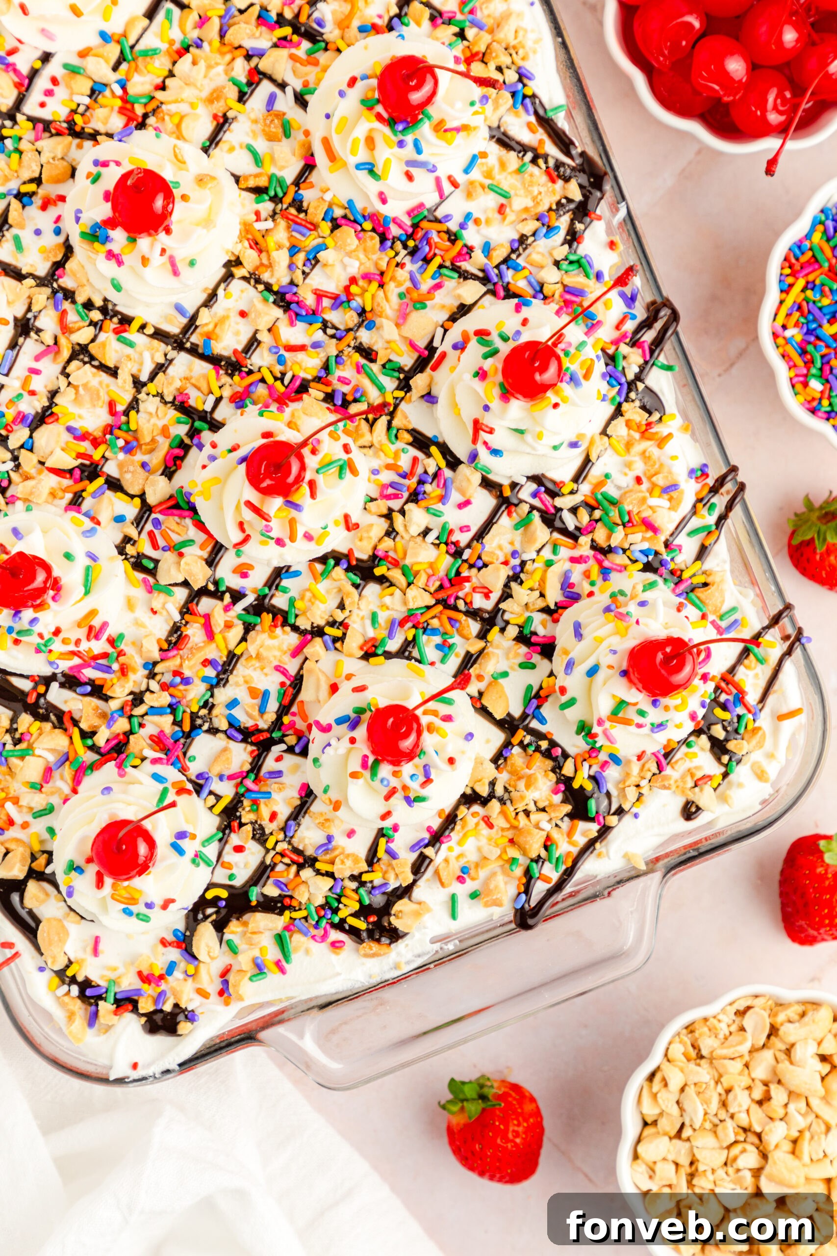A pristine overhead shot of the complete No-Bake Banana Split Cake, generously adorned with toppings, in a clear rectangular baking dish.