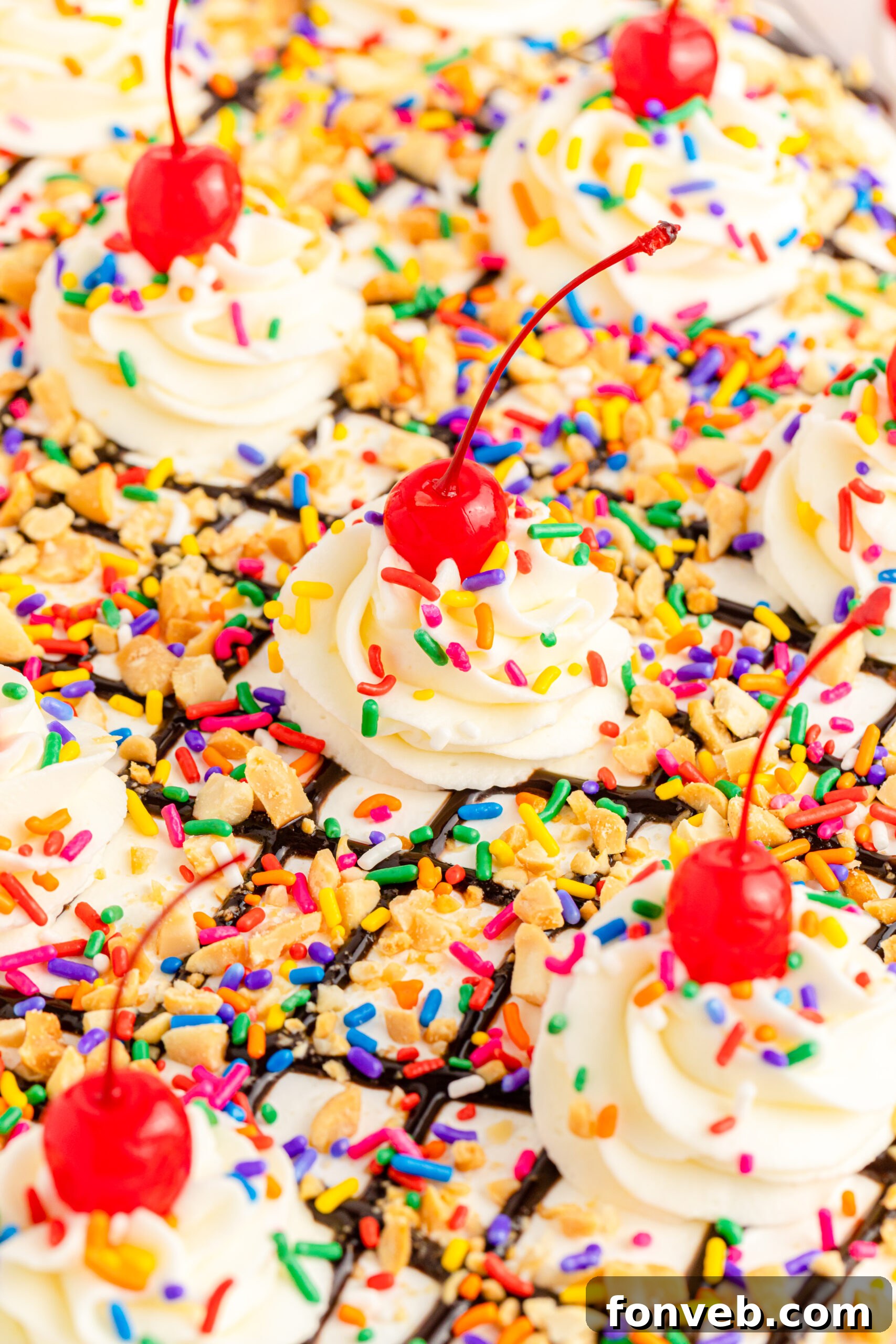 A close-up view revealing the beautiful layers of the No-Bake Banana Split Cake, showing the graham cracker crust, thick cream cheese layer, and fruit medley.