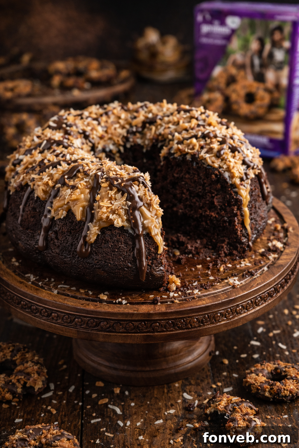 Whole Samoa Cake with a slice missing on a pretty wood cake stand on a dark table 