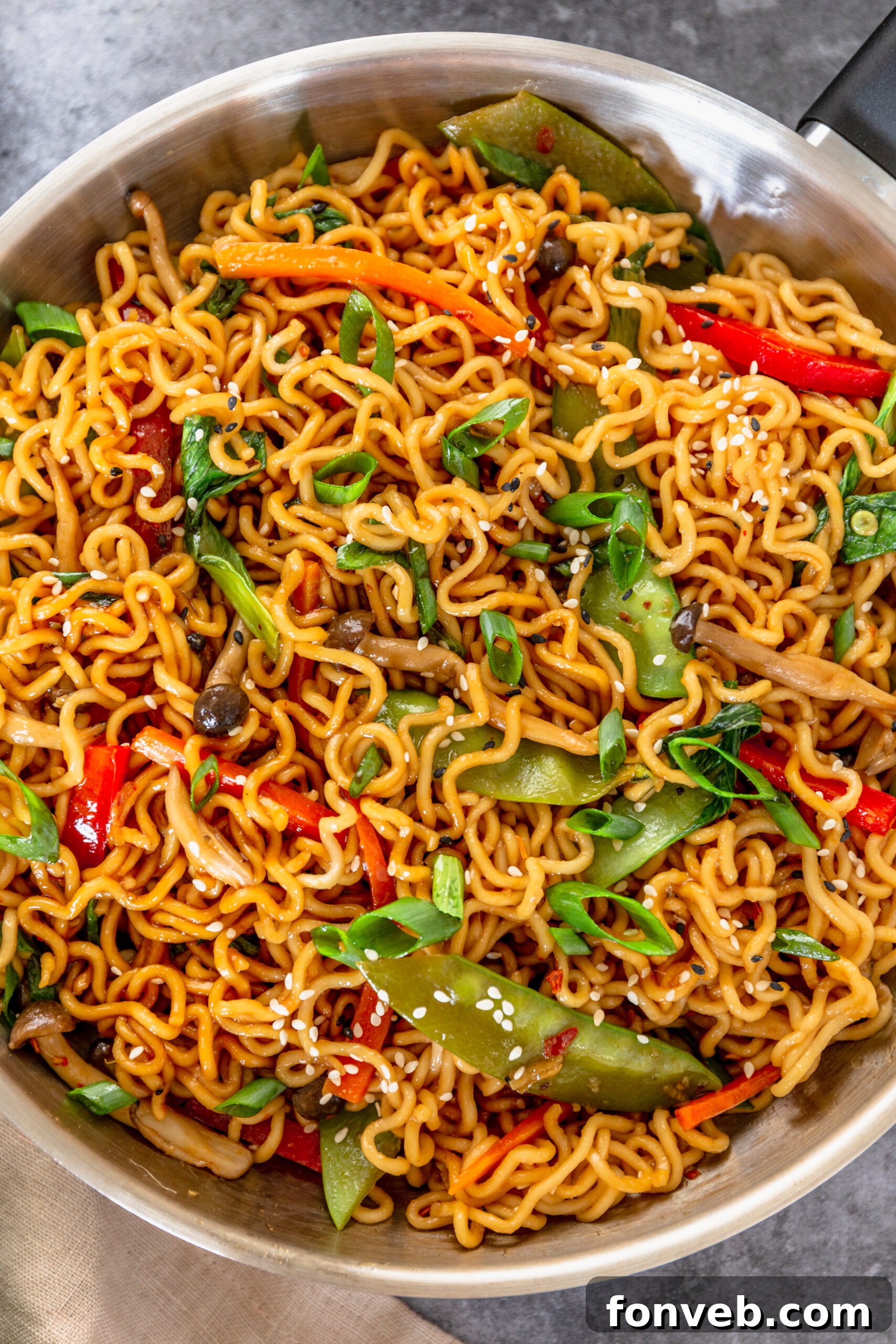Ramen Stir Fry in a silver frying pan topped with sesame seeds. 