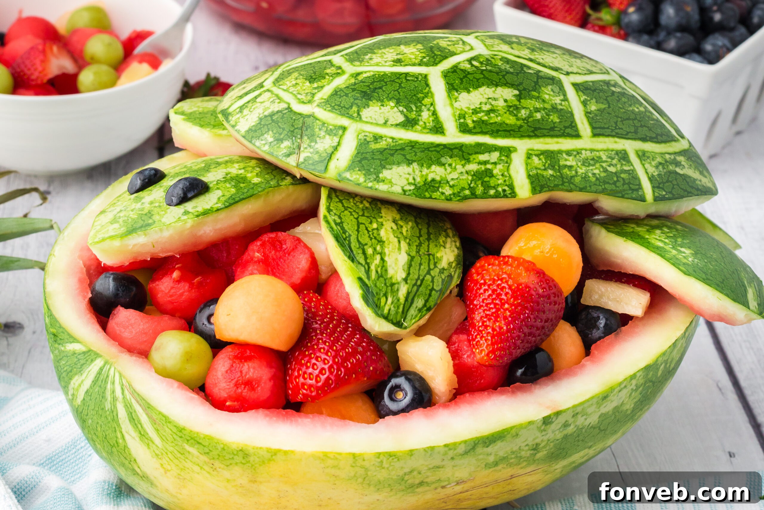 Side view of the delightful watermelon turtle salad sitting on a rustic white wood table, ready for enjoyment.