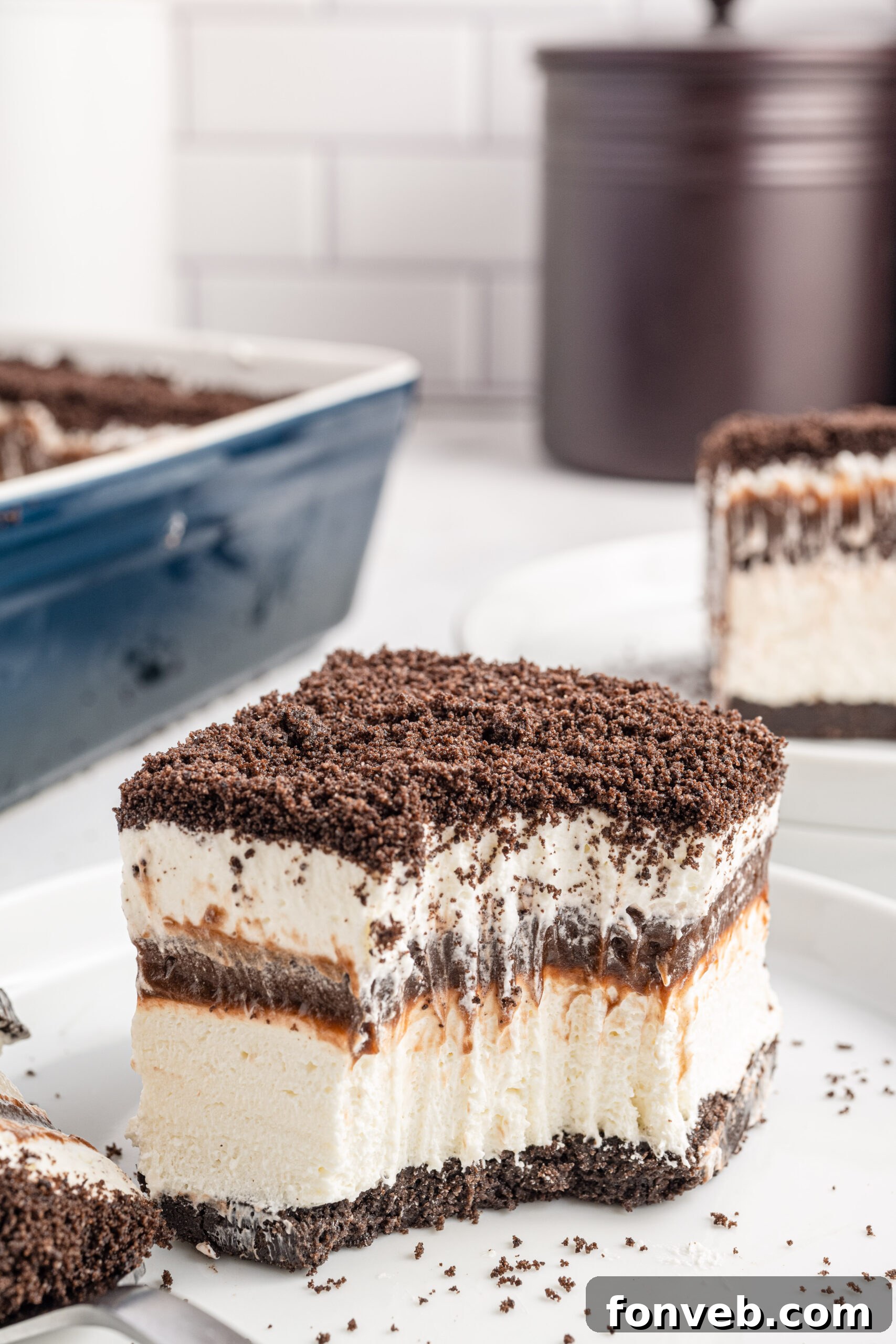 Front view of a slice of Oreo Delight on a white plate with a bite removed by a silver fork.