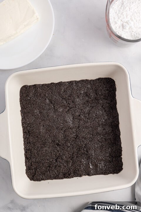 Cream cheese, powdered sugar, and vanilla extract being beaten in a bowl.