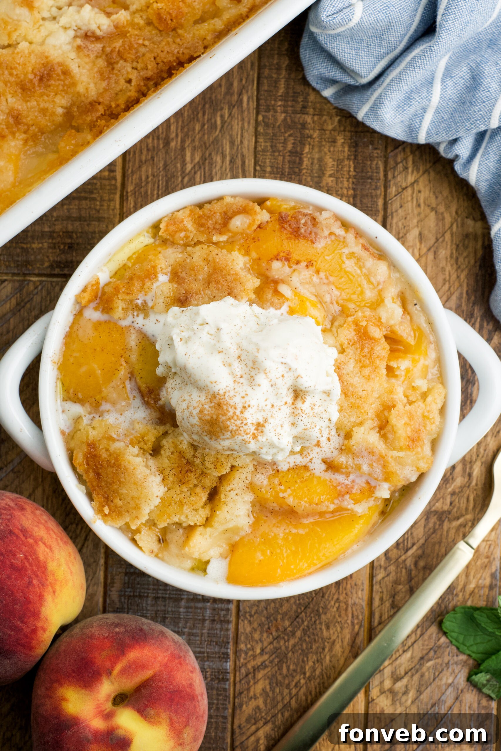 Simple Peach Dump Cake 15 Overhead view of a serving of Peach Dump Cake in a white bowl topped with a scoop of vanilla ice cream.