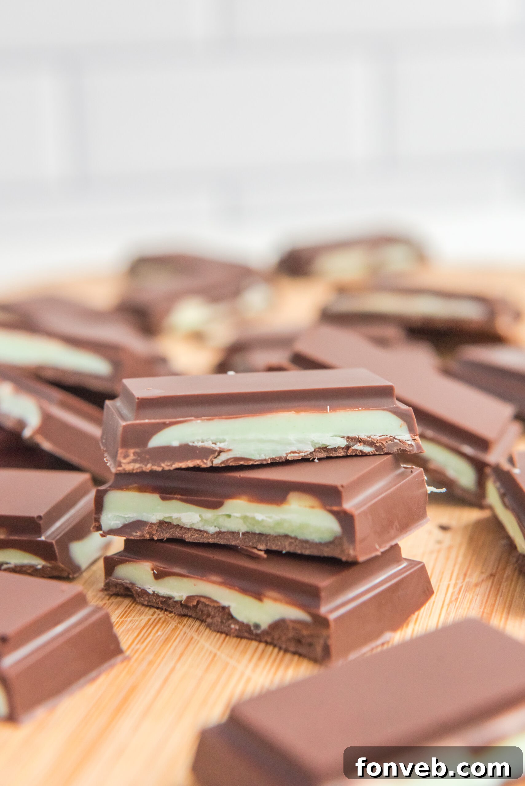 Front view of three Homemade Andes Mints stacked on a wooden cutting board.