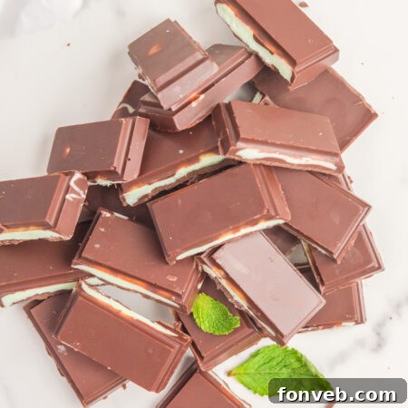 Stack of Homemade Andes Mints with a bite taken out of one, on a wooden board.