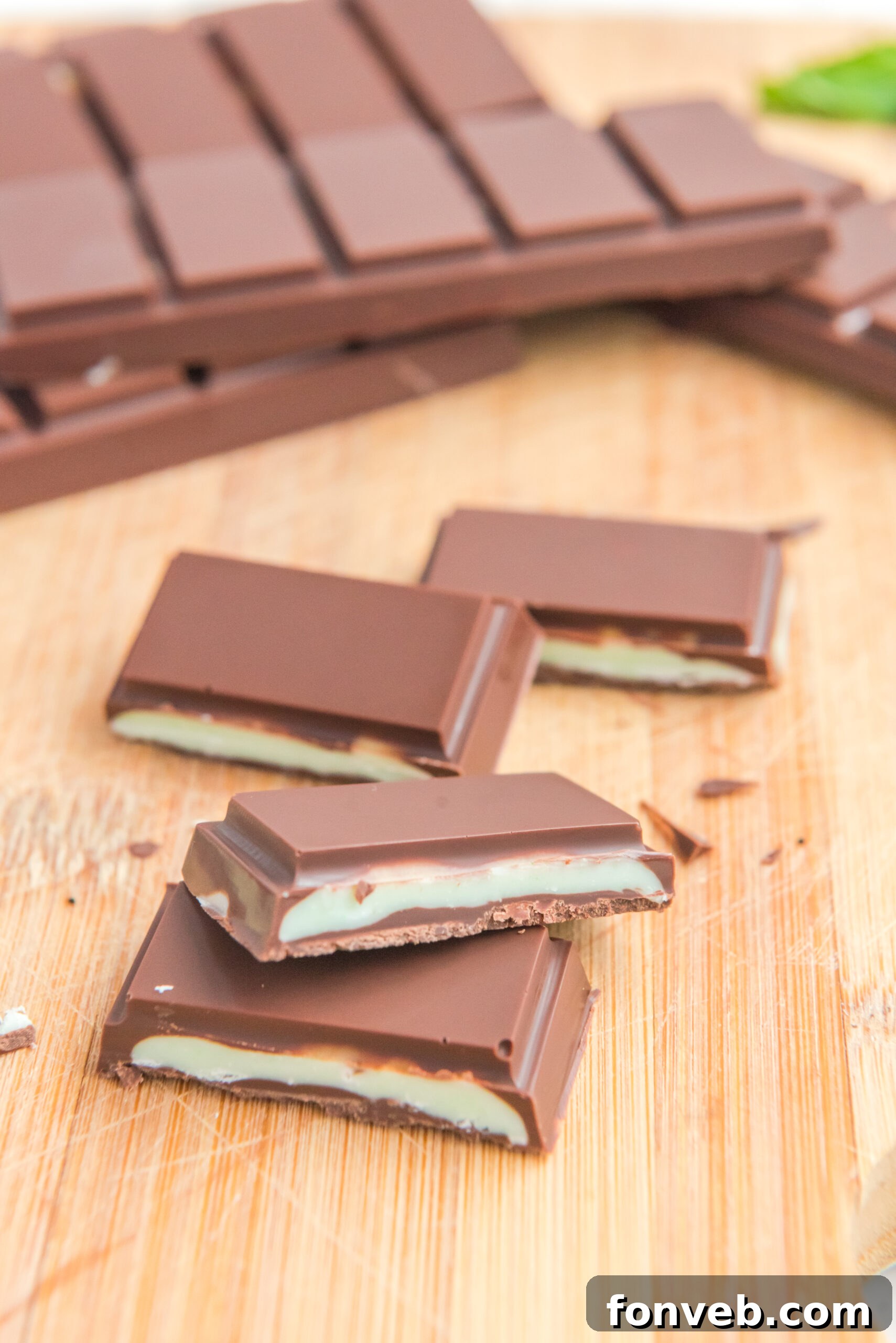 Front view of two Homemade Andes Mints stacked on a wooden cutting board.