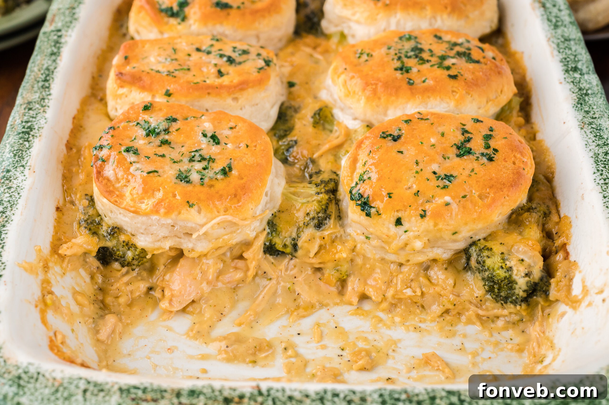 Close up view of Broccoli Cheddar Biscuit Casserole in a baking dish with two full servings removed.