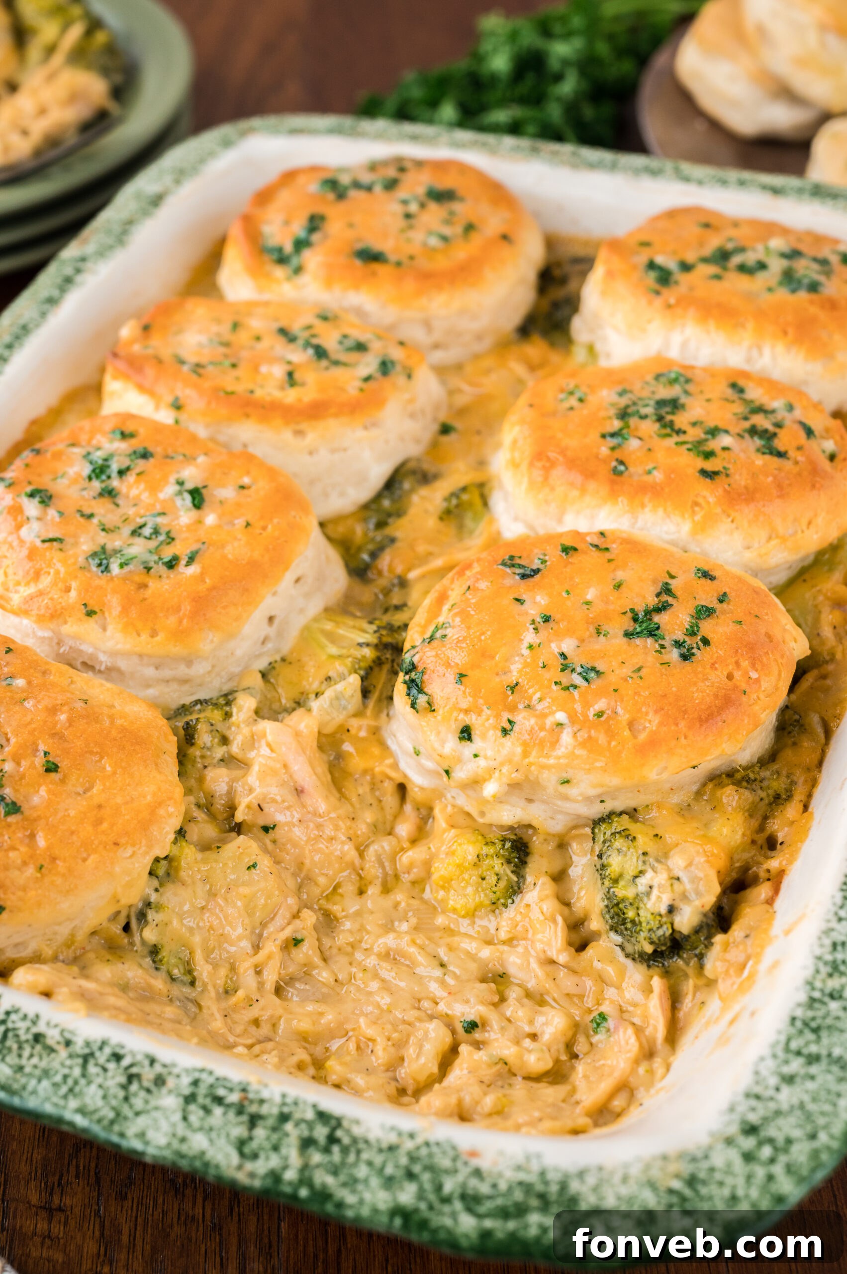 Close up view of Broccoli Cheddar Biscuit Casserole in a baking dish with one biscuit removed.