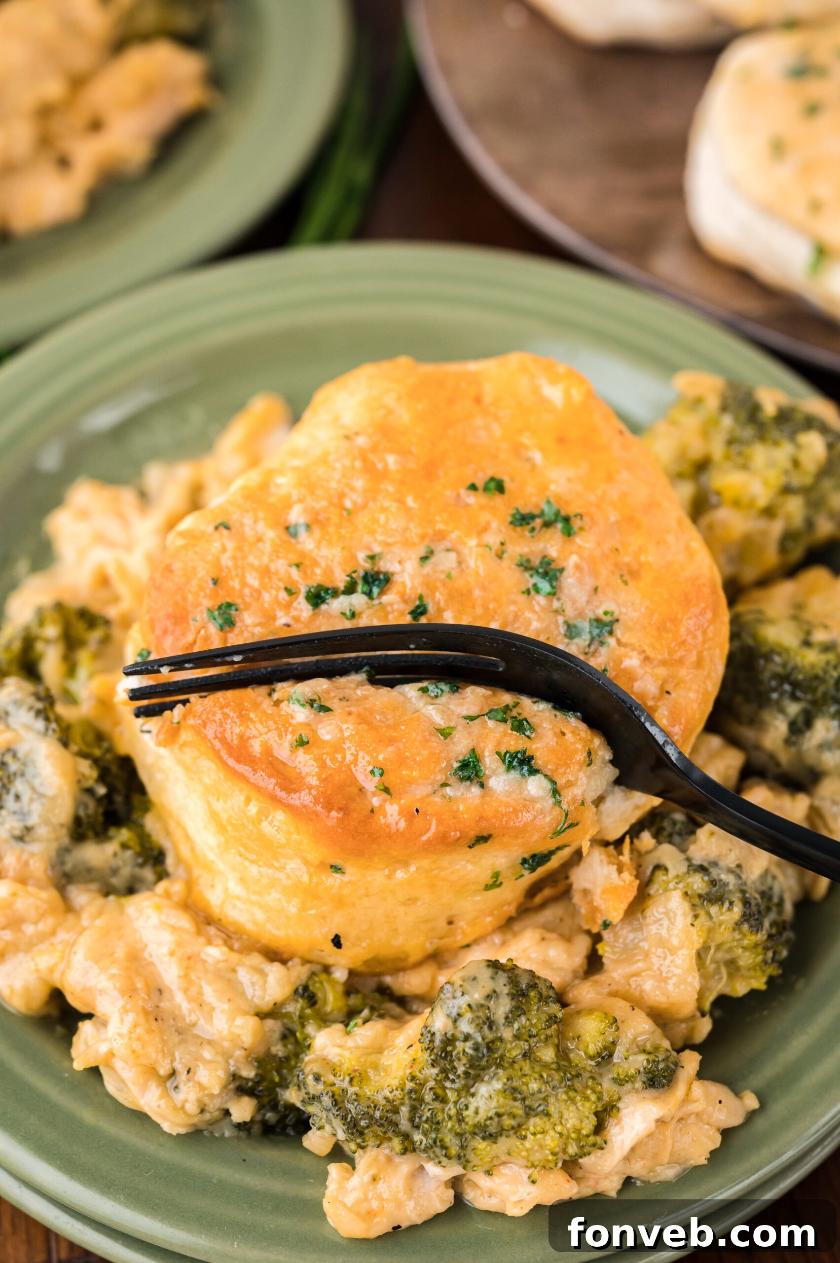 Close up view of a black fork removing a bite from a serving of Broccoli Cheddar Biscuit Casserole.