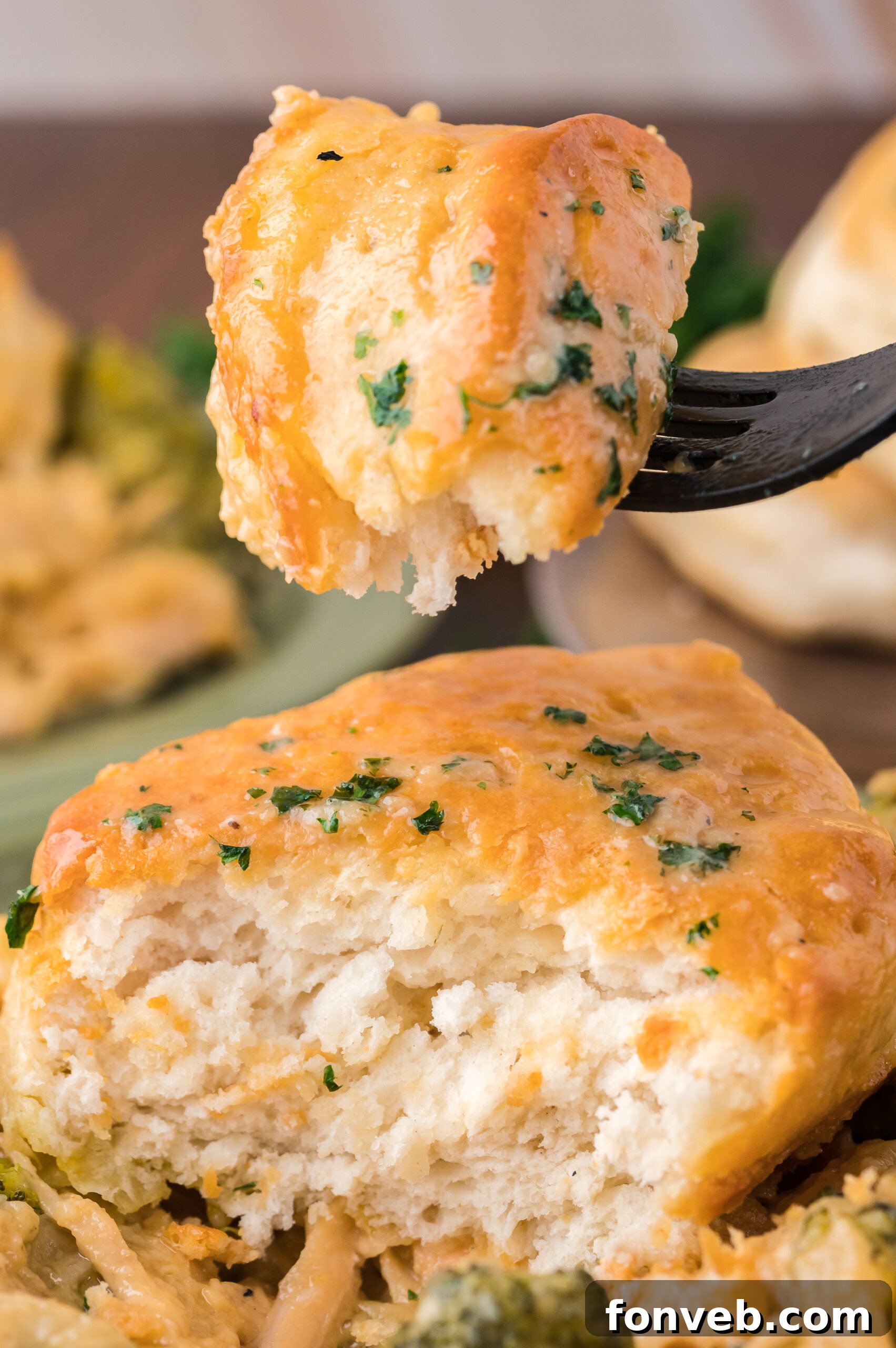 Close up view of a bite of Broccoli Cheddar Biscuit Casserole on a black fork.