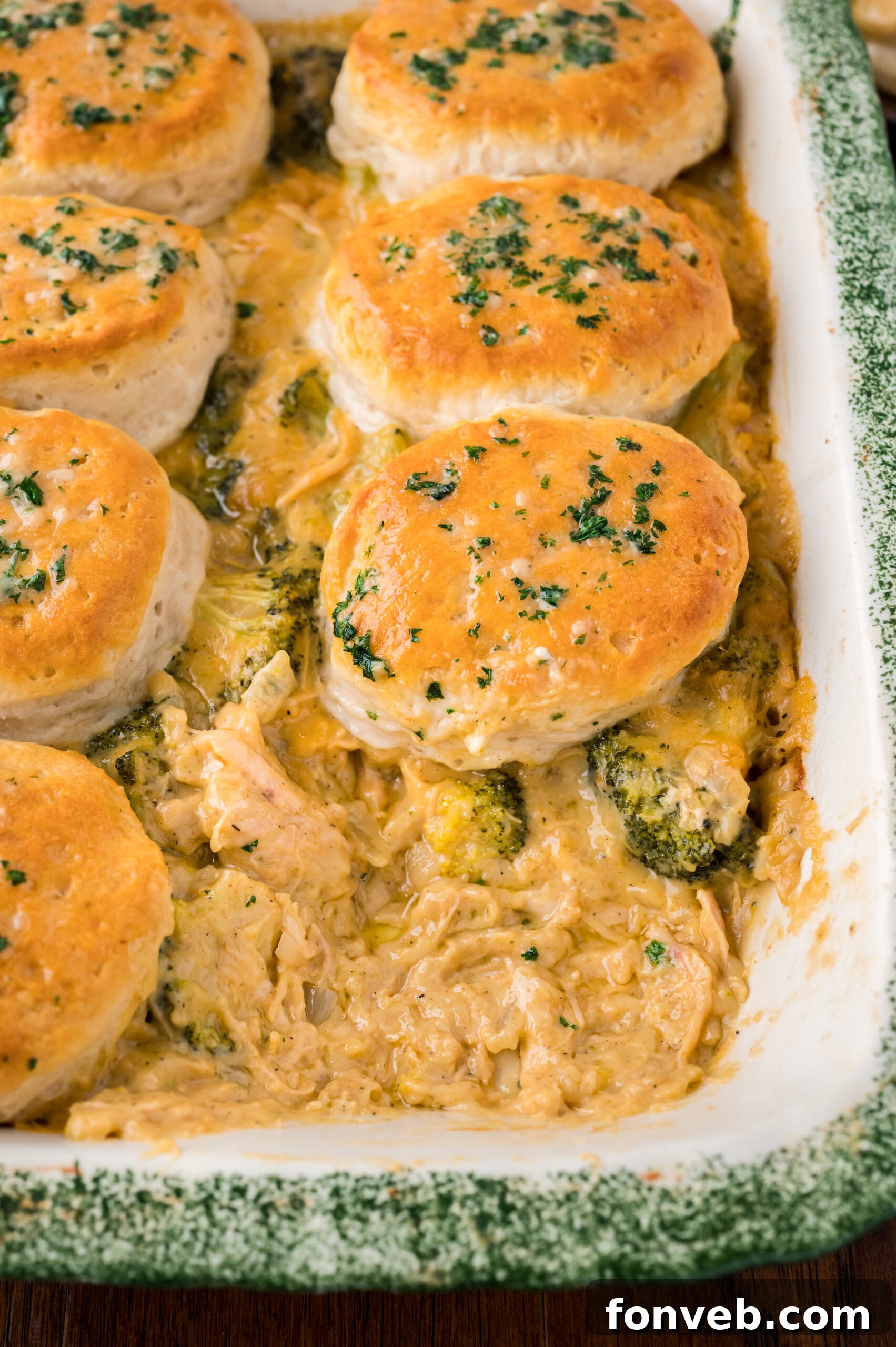 Close up view of Broccoli Cheddar Biscuit Casserole in a baking dish with one serving removed.