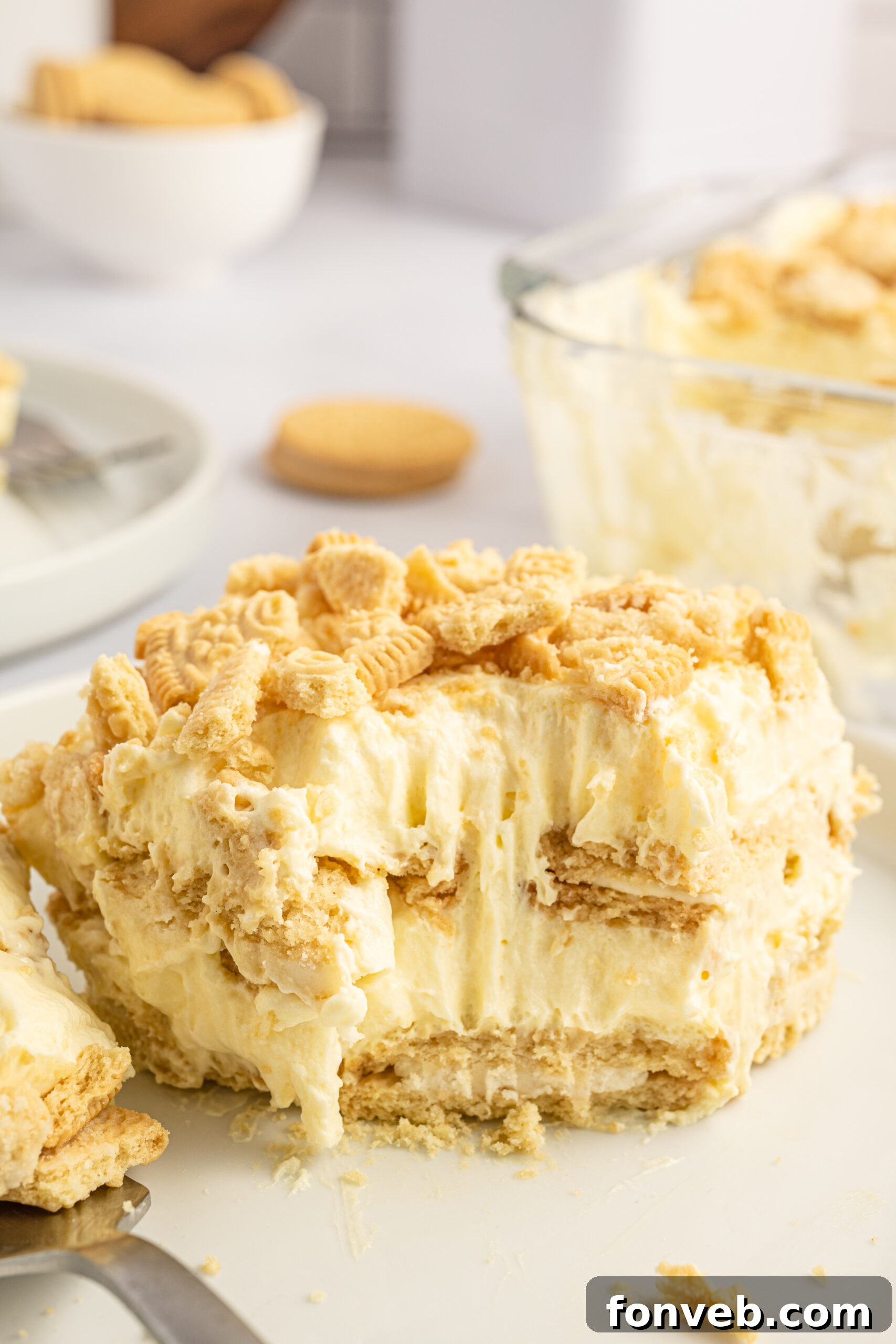 Golden Oreo No-Bake Delight 18 Front view of a slice of Golden Oreo Icebox Cake with a bite removed by a silver fork.