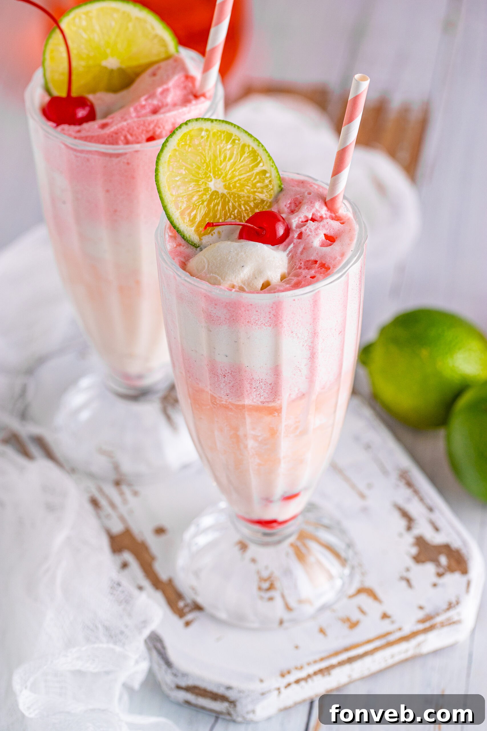 Close up view of Dirty Shirley Float in a clear glass topped with a lime slice and cherry.