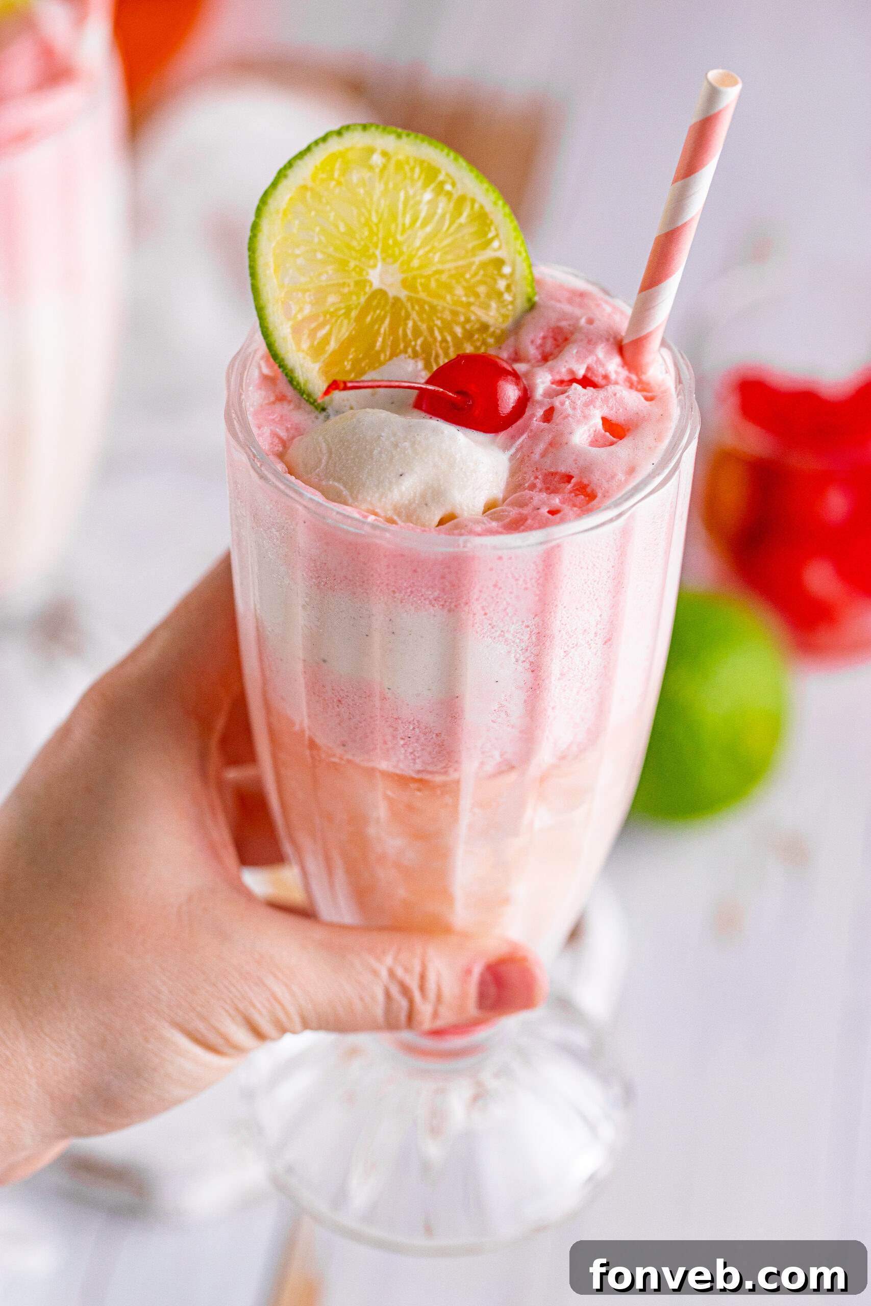Close up view of Dirty Shirley Float in a clear glass topped with a lime slice and cherry.