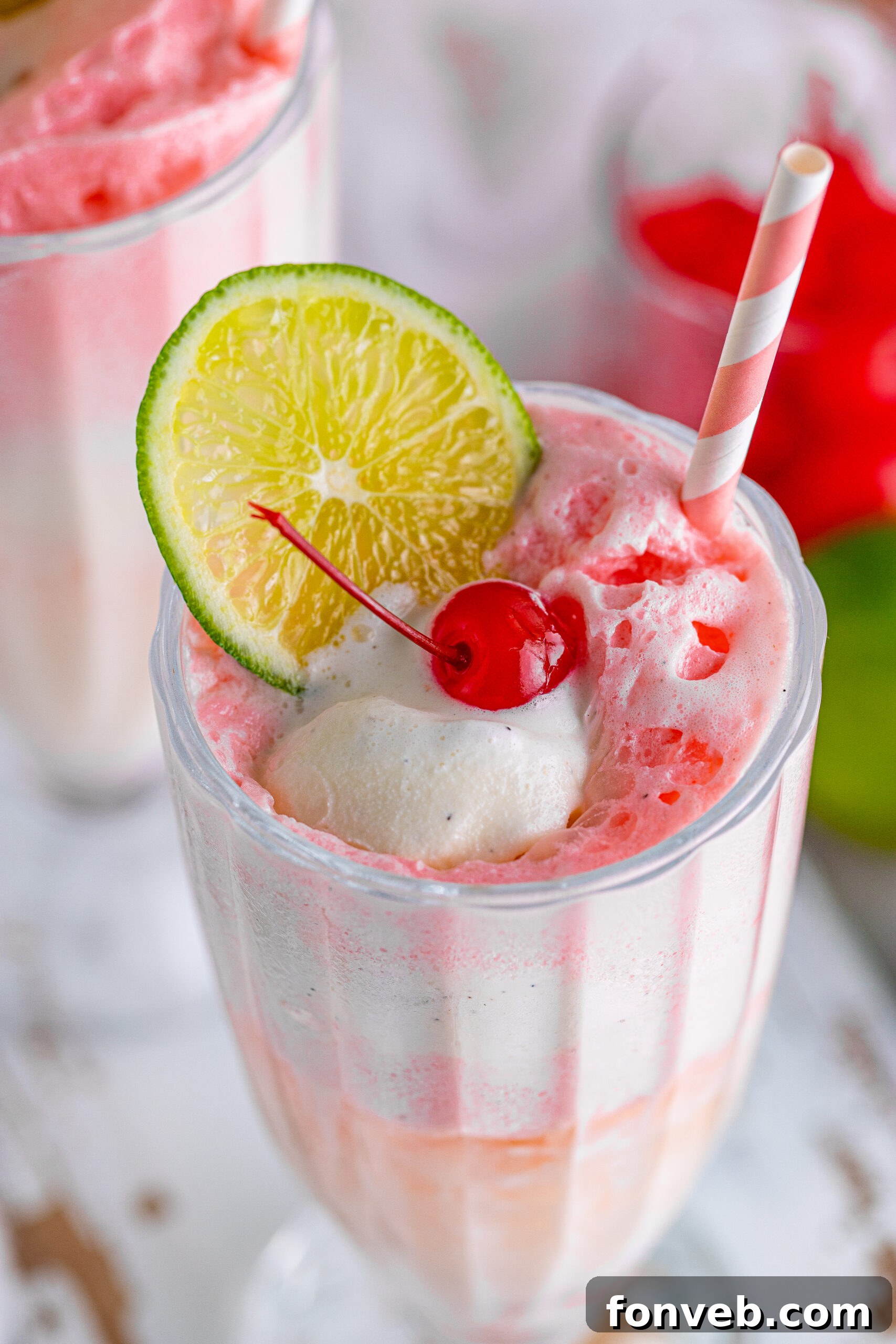 Close up view of Dirty Shirley Float in a clear glass topped with a lime slice and cherry.