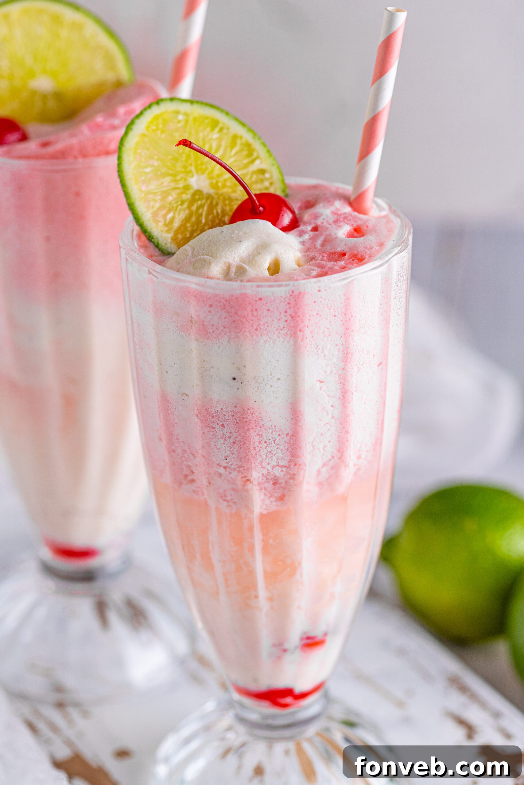 Close up view of Dirty Shirley Float in a clear glass topped with a lime slice and cherry.