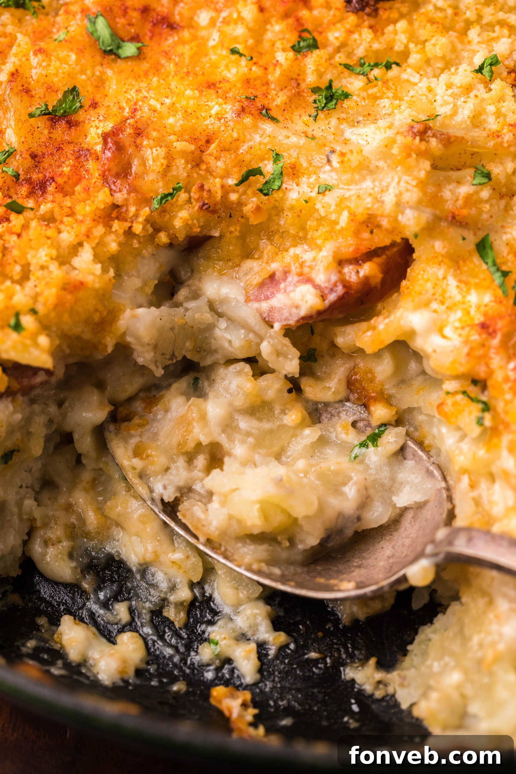 Creamy Sausage and Potato Gratin 7 Au Gratin Potatoes & Sausage in a cast iron skillet with a spoon scooping some