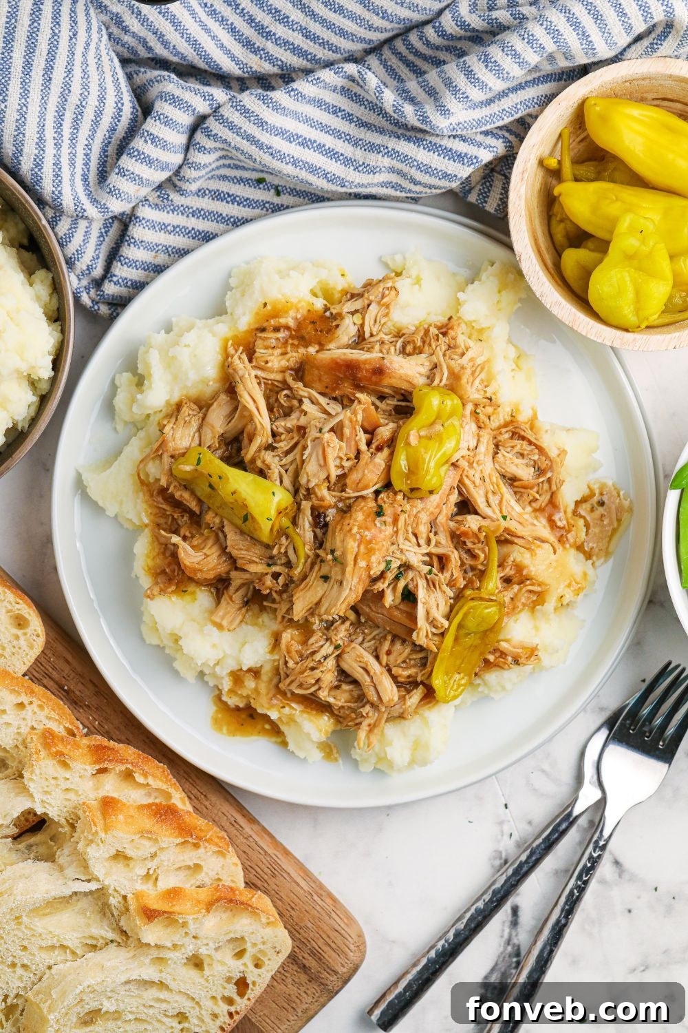 overhead shot of chicken and mashed potatoes on plate with bread and peppers around it 