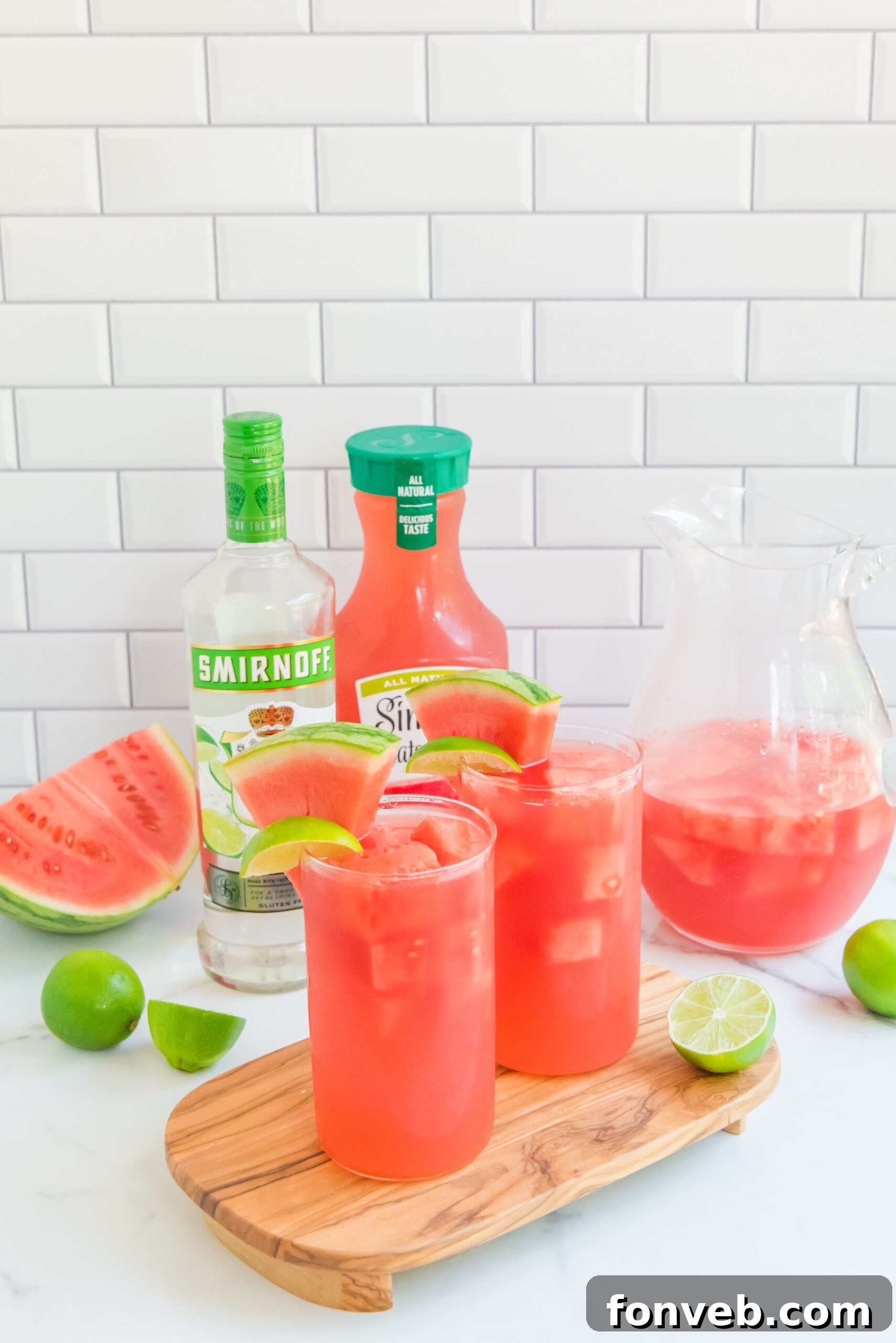 Front view of Watermelon Cocktail in two clear glasses garnished with lime and watermelon slices.